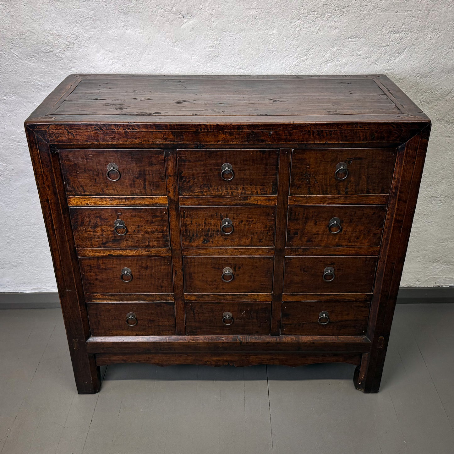 Wooden dresser with multiple drawers against a plain wall.