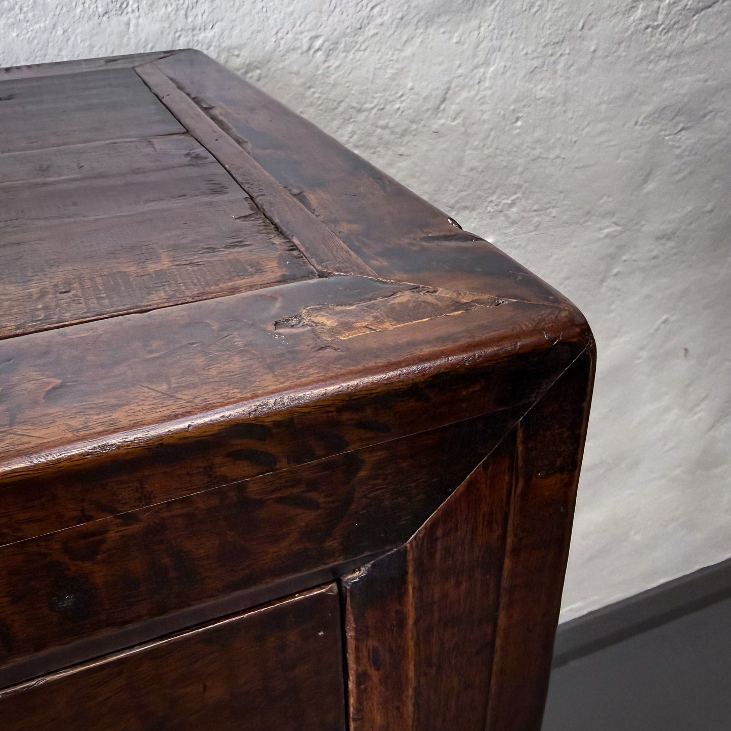 Close-up of a wooden cabinet with a textured wall background