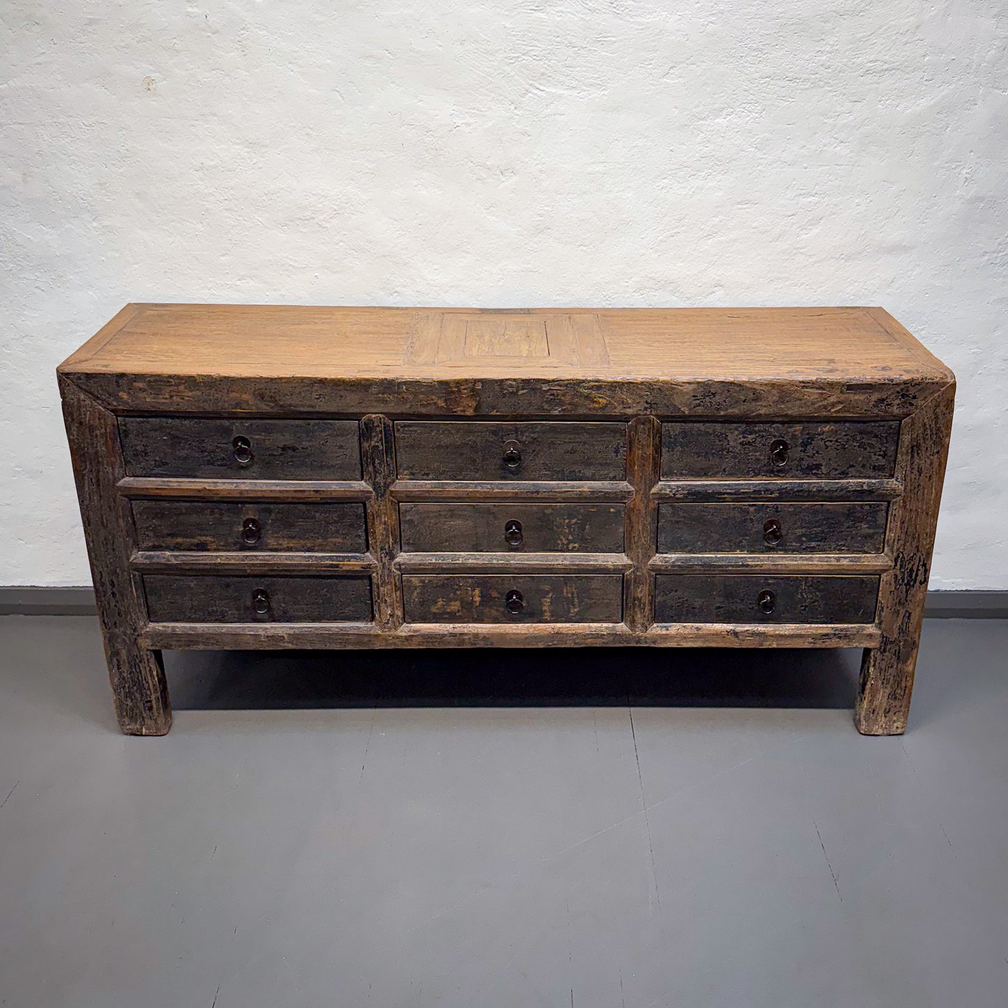 Vintage wooden dresser with multiple drawers against a plain wall.