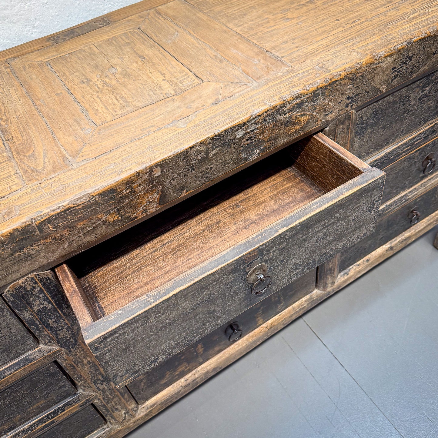 Wooden dresser with a drawer open on a light gray floor