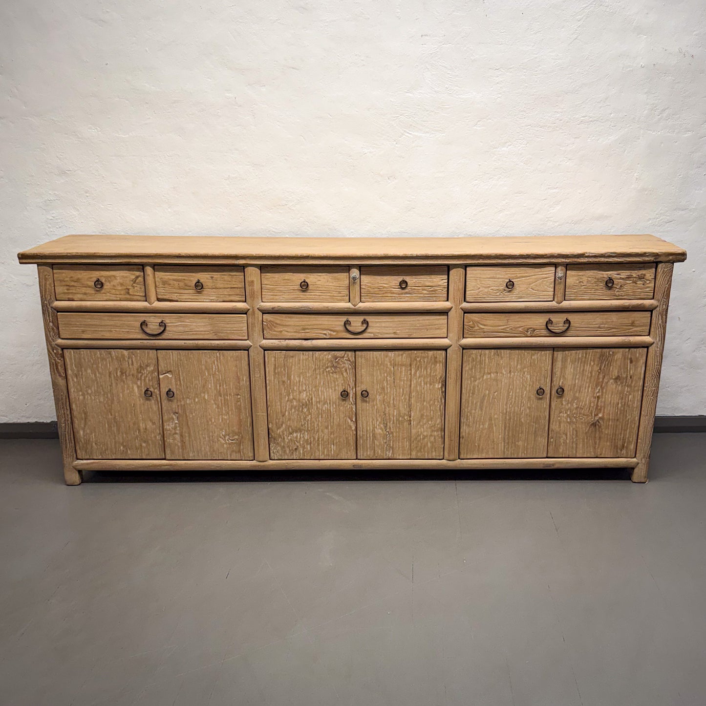 Wooden sideboard with multiple drawers and doors on a plain background