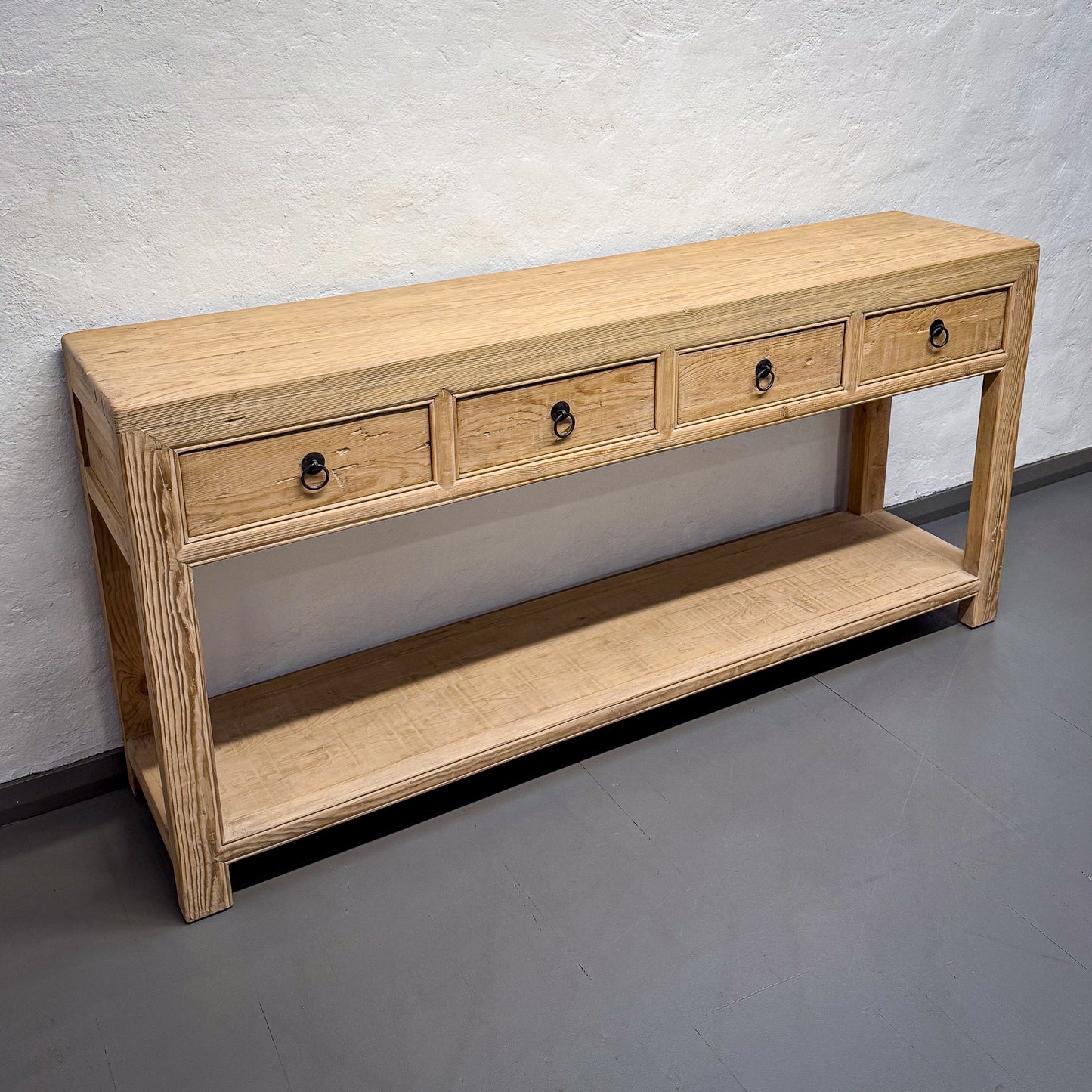 Wooden console table with drawers against a plain wall.