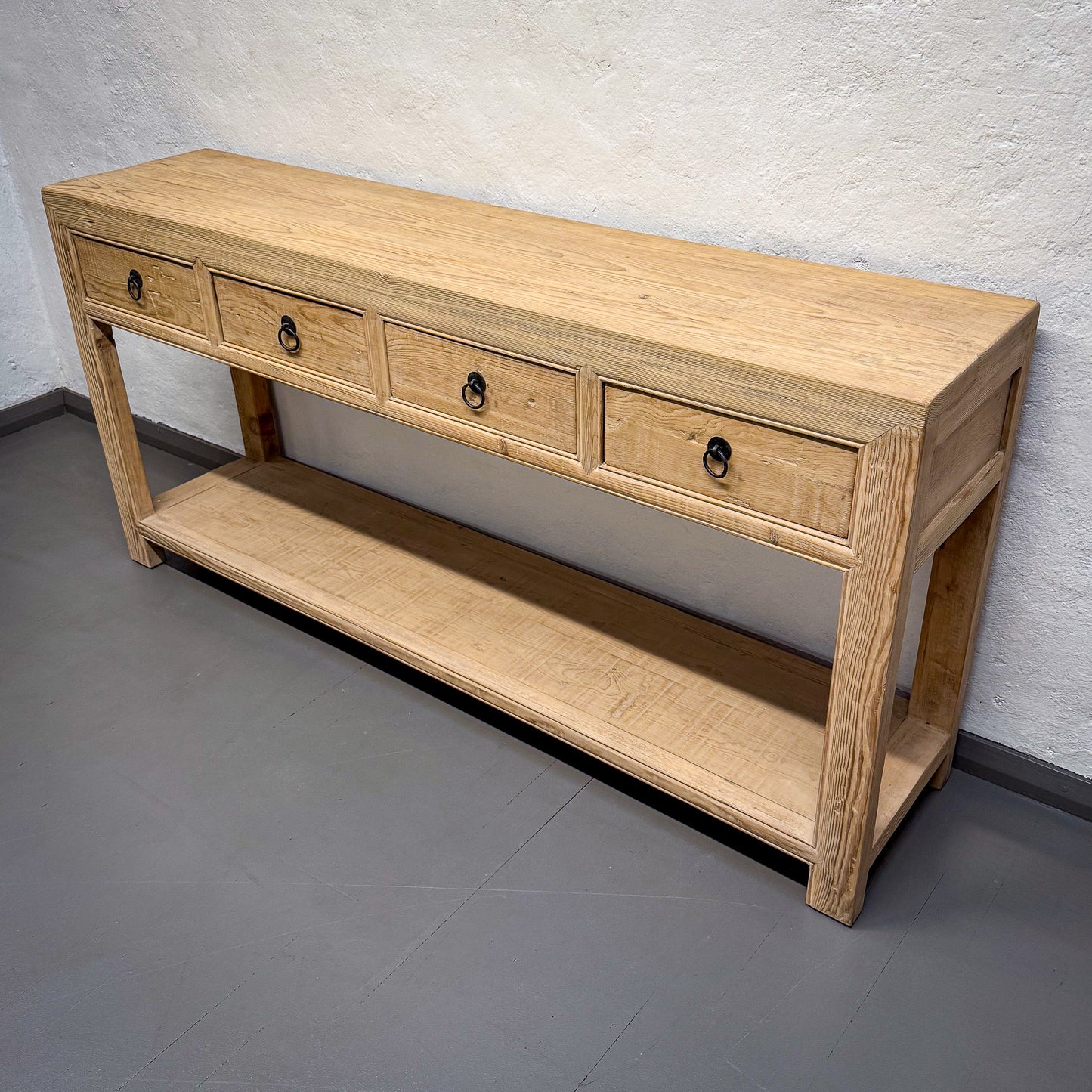 Wooden console table with drawers against a plain wall.
