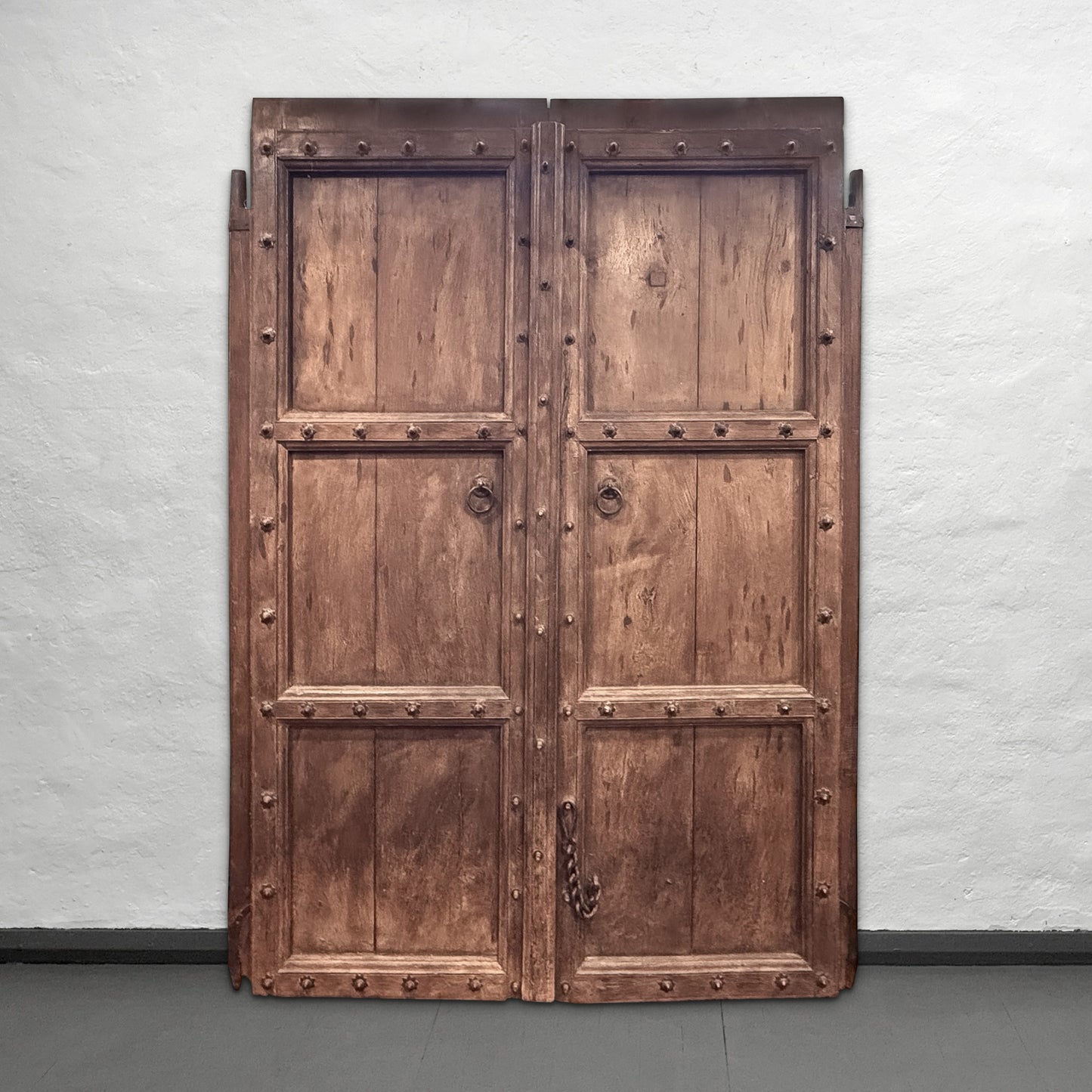 Wooden door with metal accents on a plain wall
