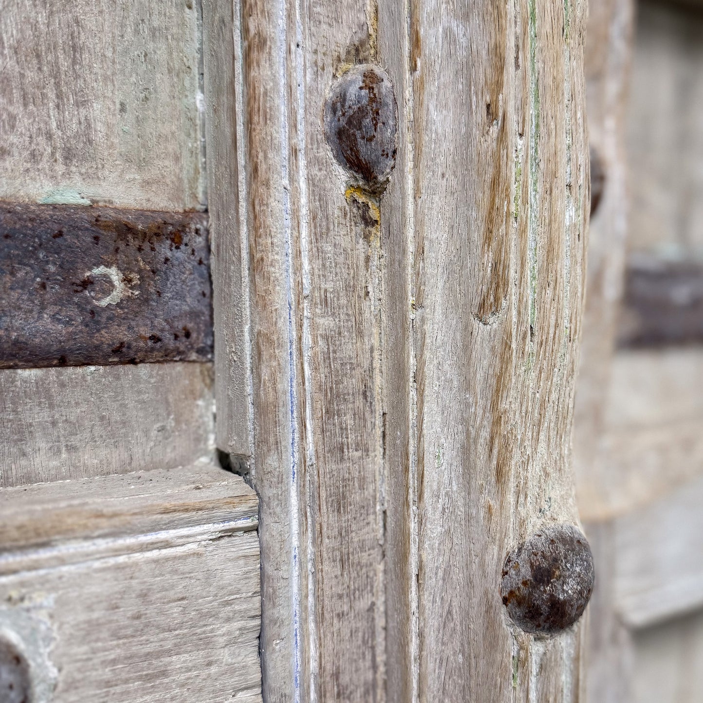 Close-up of a wooden door with metal bars and peeling paint