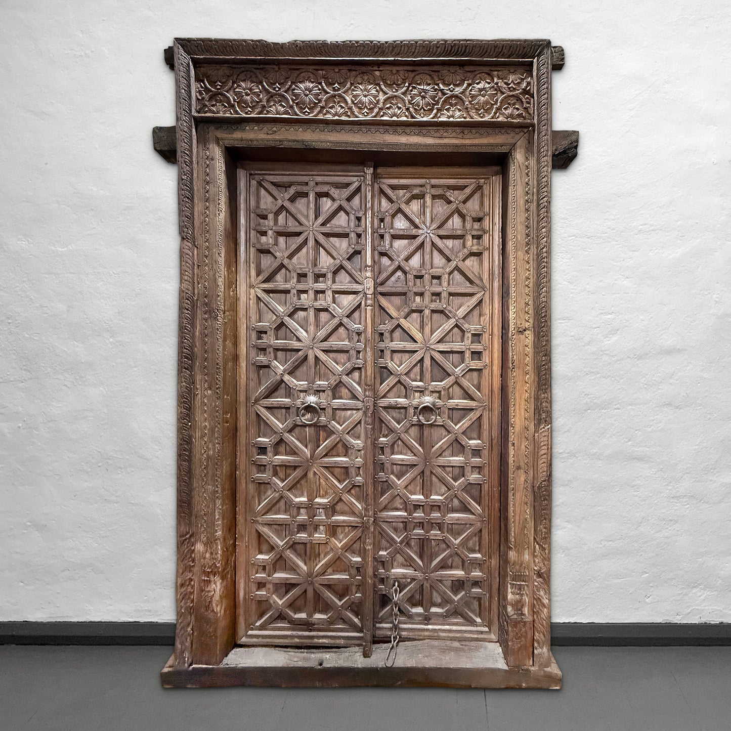 Decorative wooden door with intricate carvings on a plain wall.