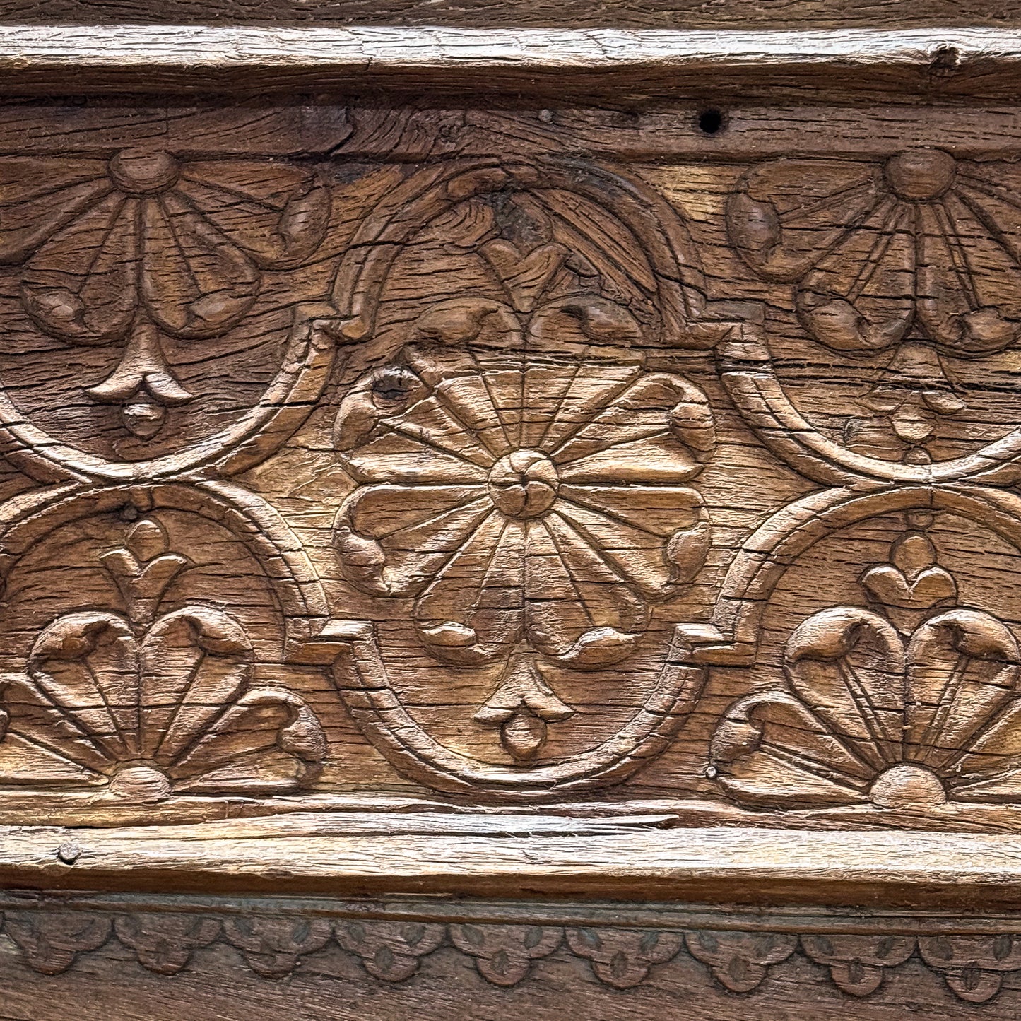 Close-up of wooden carvings with floral patterns on a wooden surface.