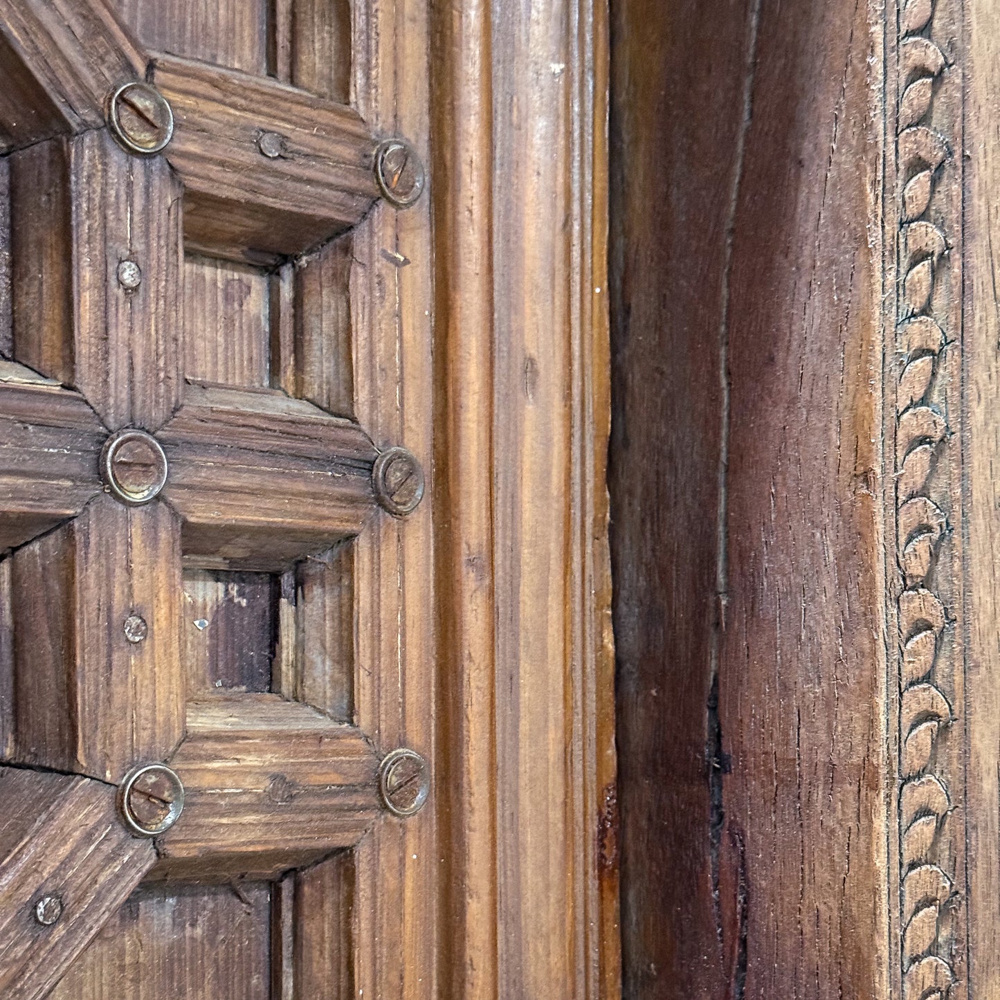 Close-up of a wooden door with intricate carvings and metal fixtures.