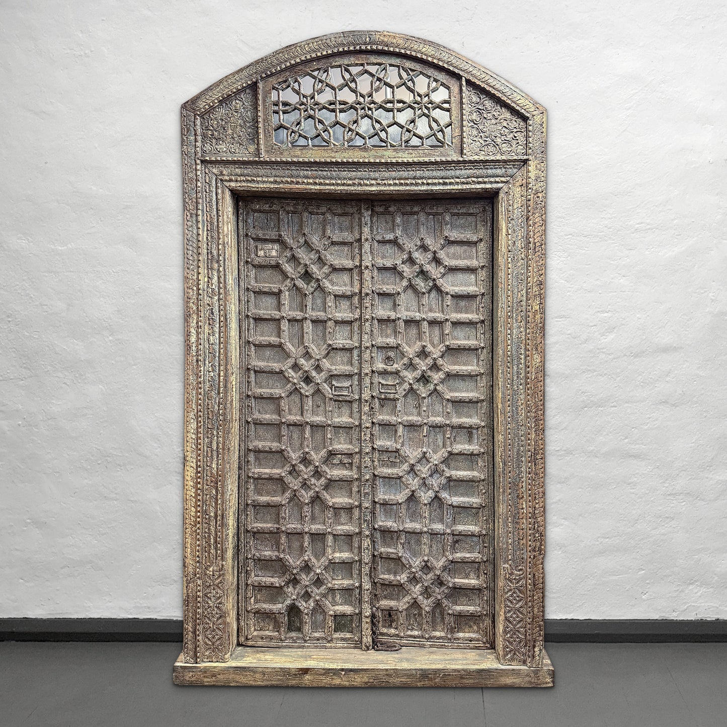 Decorative wooden panel with intricate carvings on a plain wall.