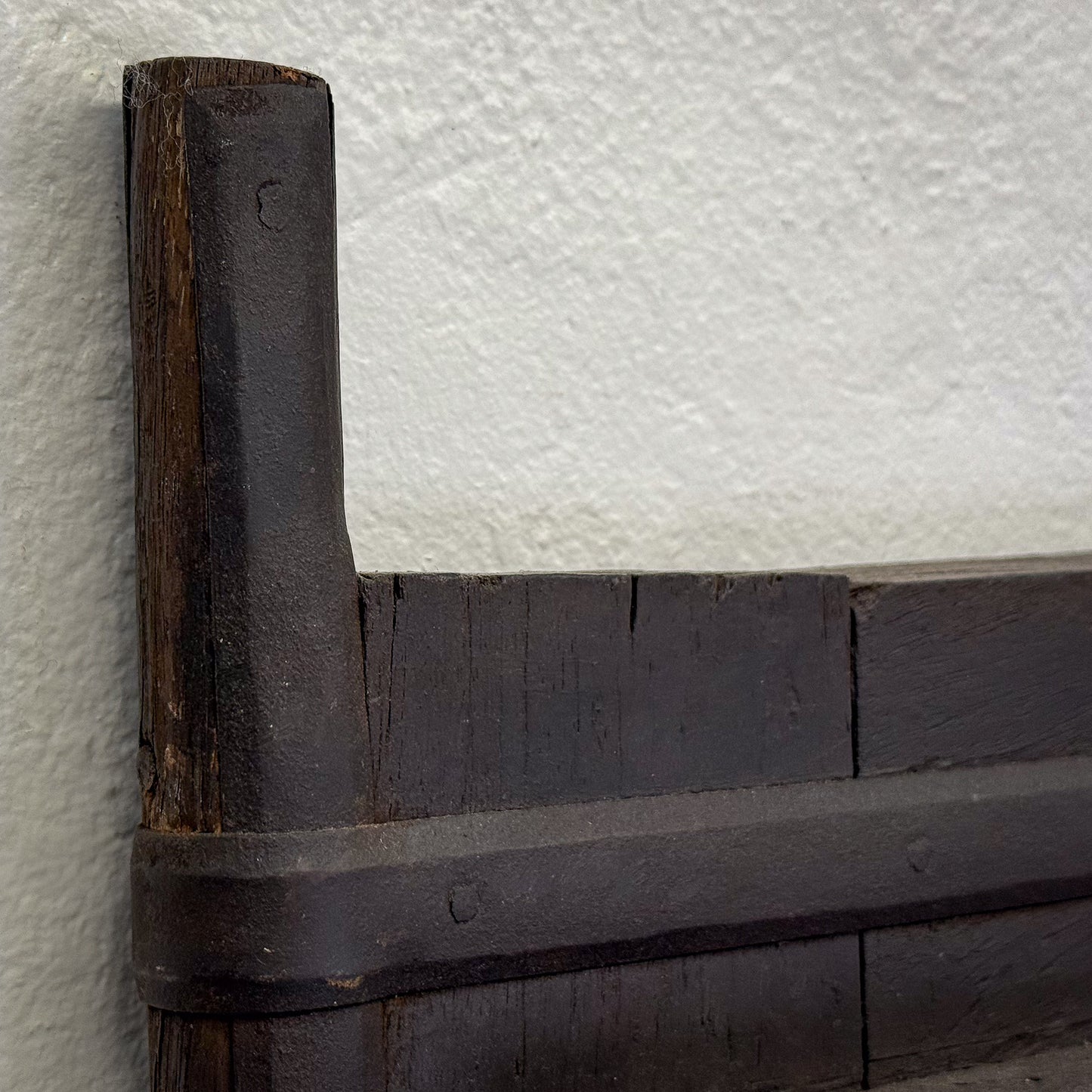 Close-up of a wooden corner bracket against a textured white background