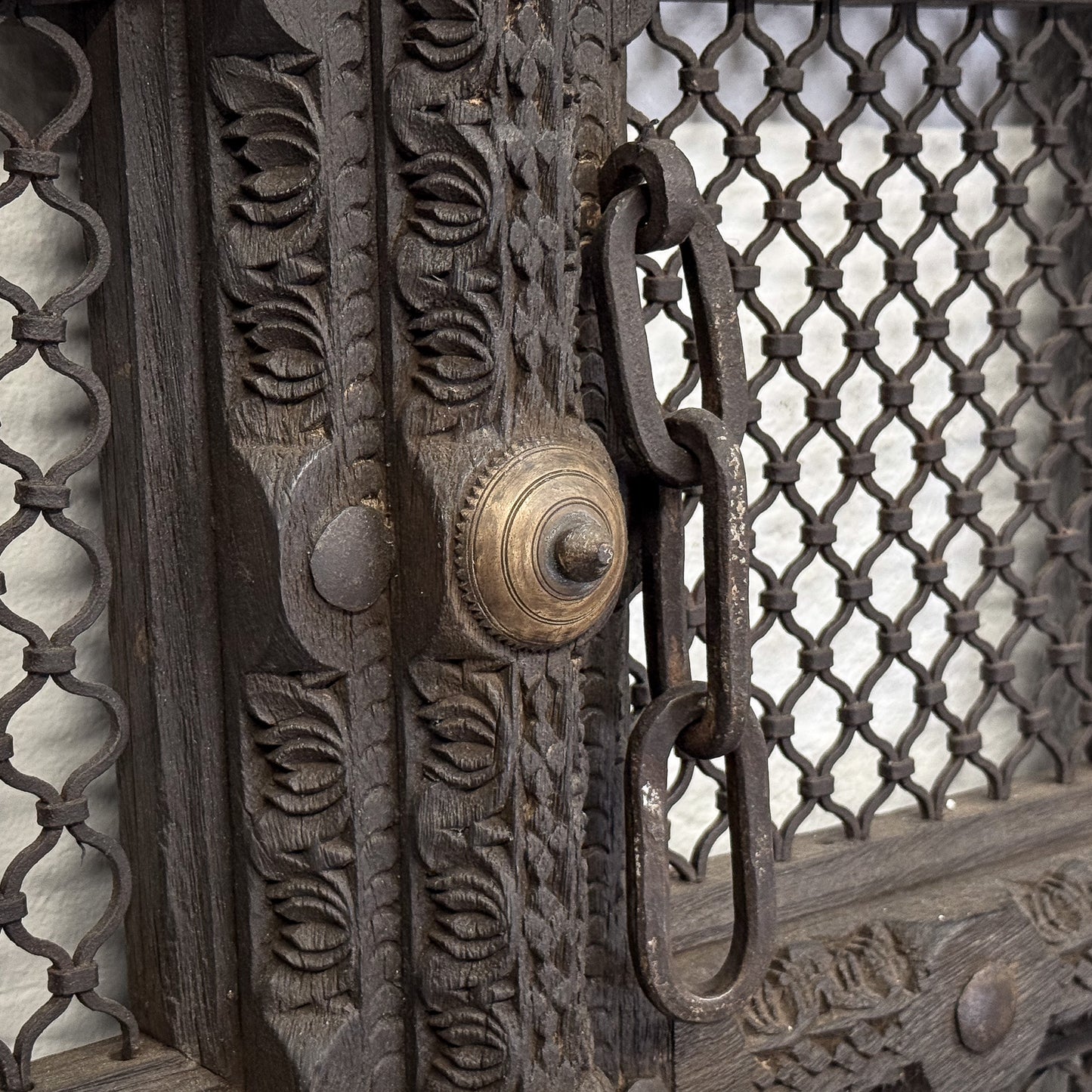 Decorative metal gate with intricate patterns and a brass doorknob.