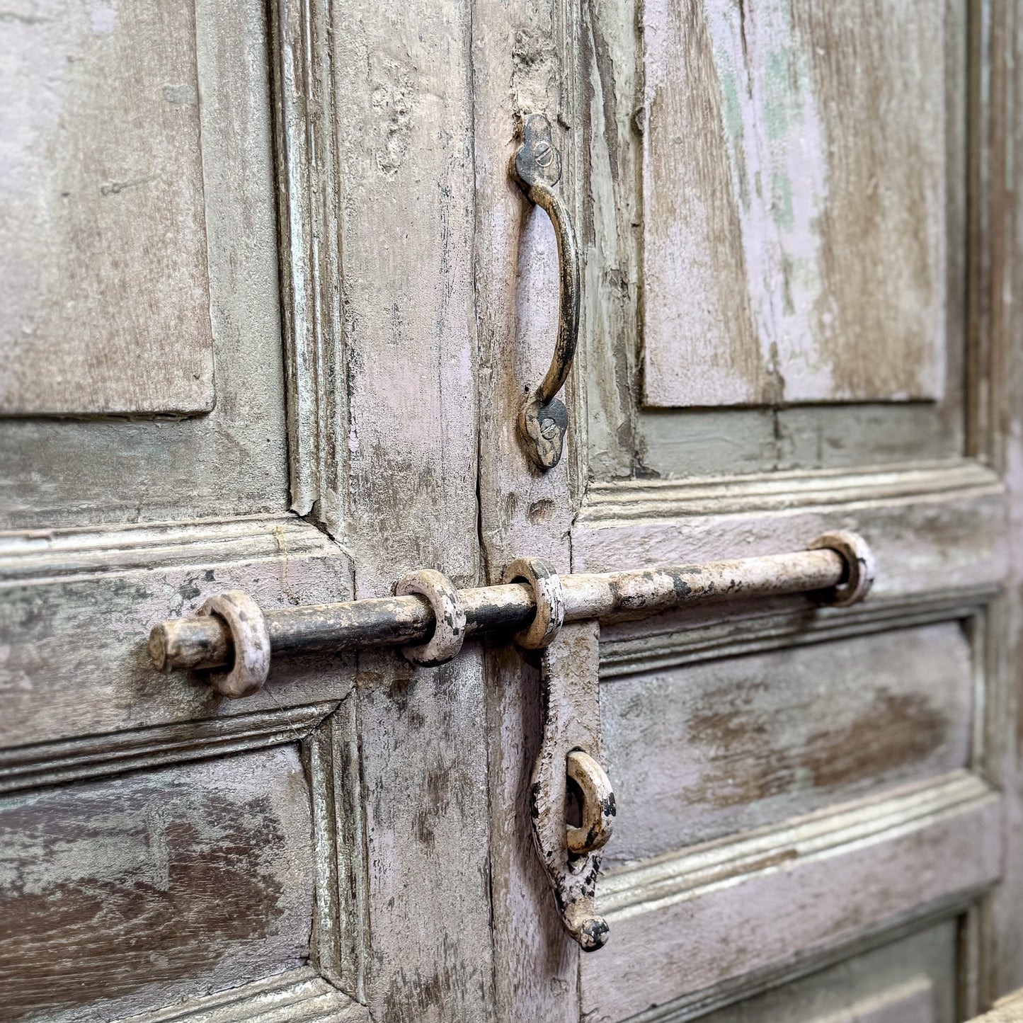Close-up of an old wooden door with a rusty metal lock and handle.