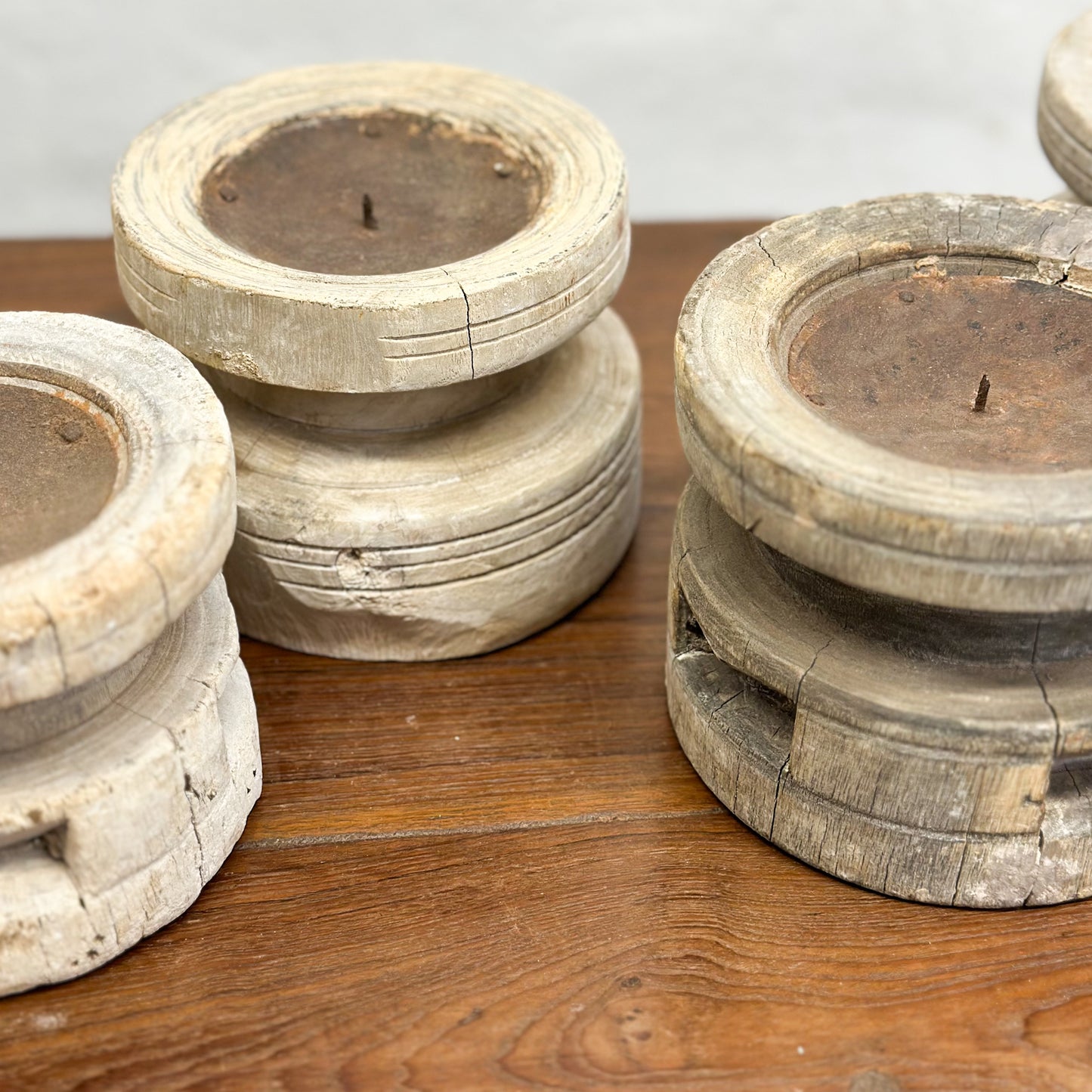 A set of three bleached wooden candle holders in different sizes placed on a wooden surface.