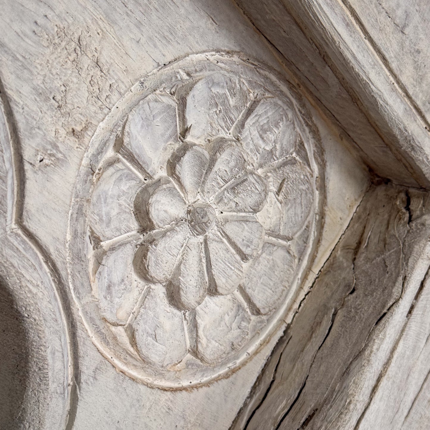 Decorative stone carving of a floral pattern on a textured wall.