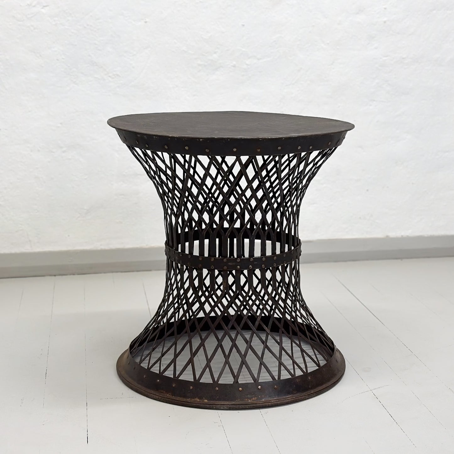 A round iron lattice side table with a dark finish, displayed against a neutral background.