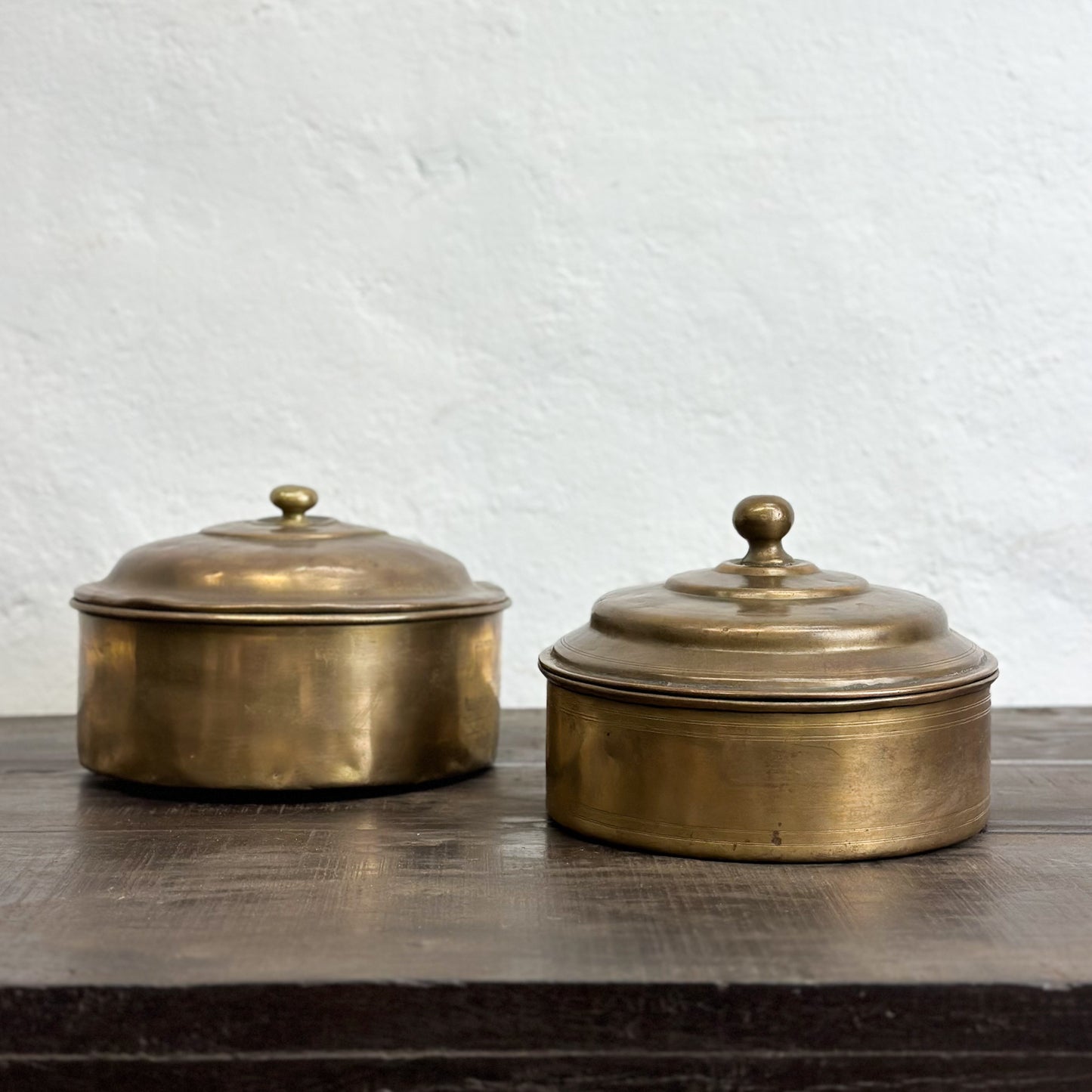 Two brass knob lid chapati boxes with a plain background.
