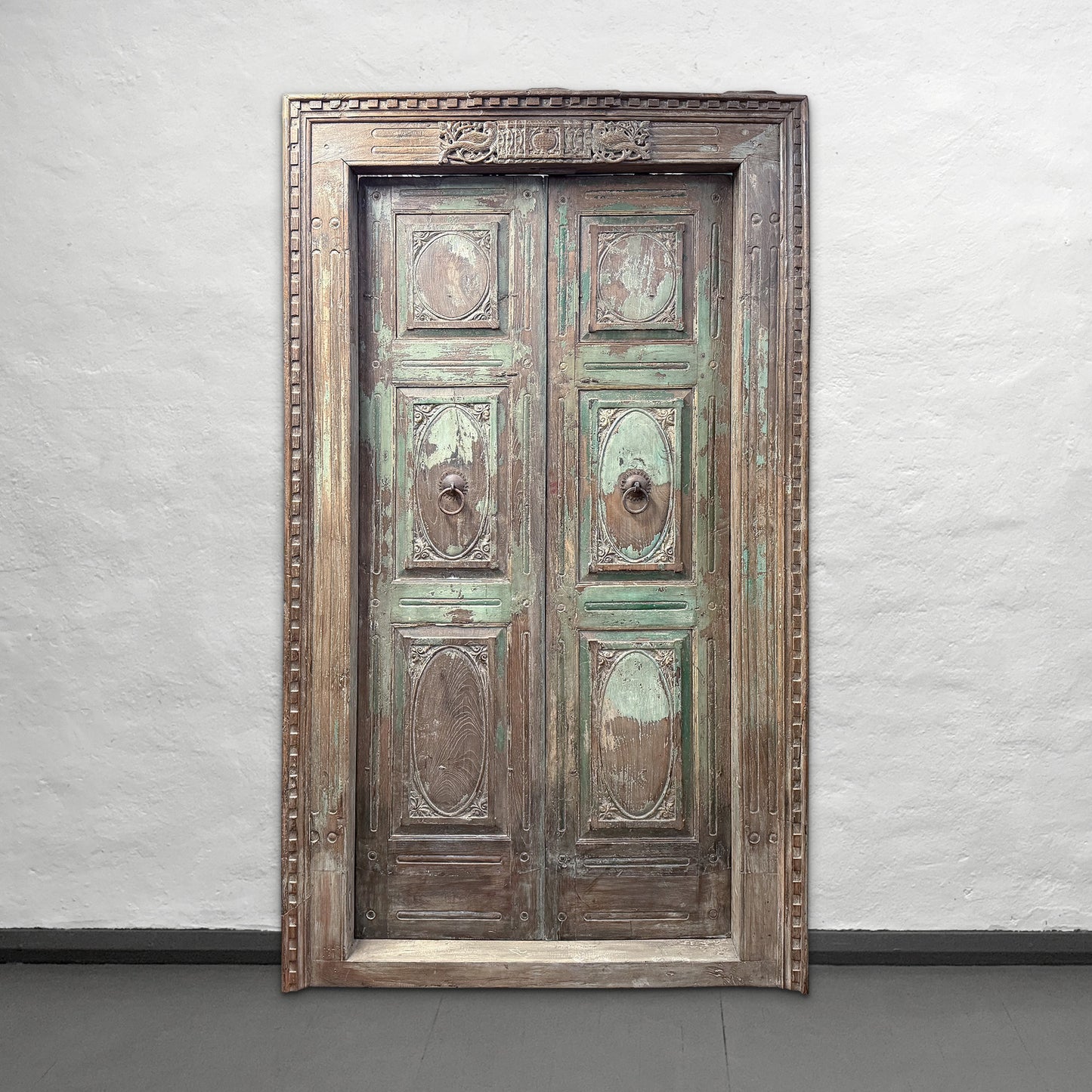 Vintage wooden door with decorative frame against a plain wall