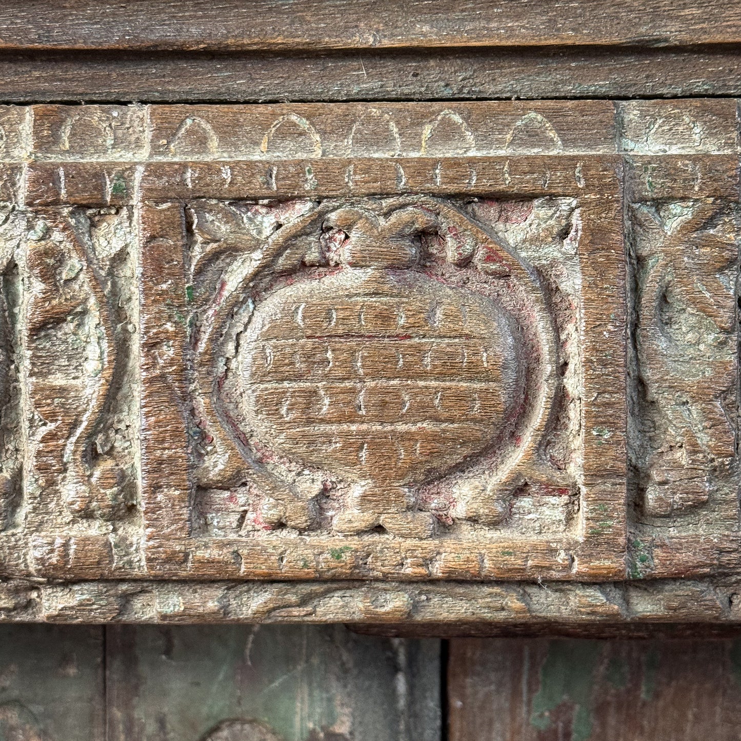 Wooden panel with intricate carvings and a central emblem-like design.