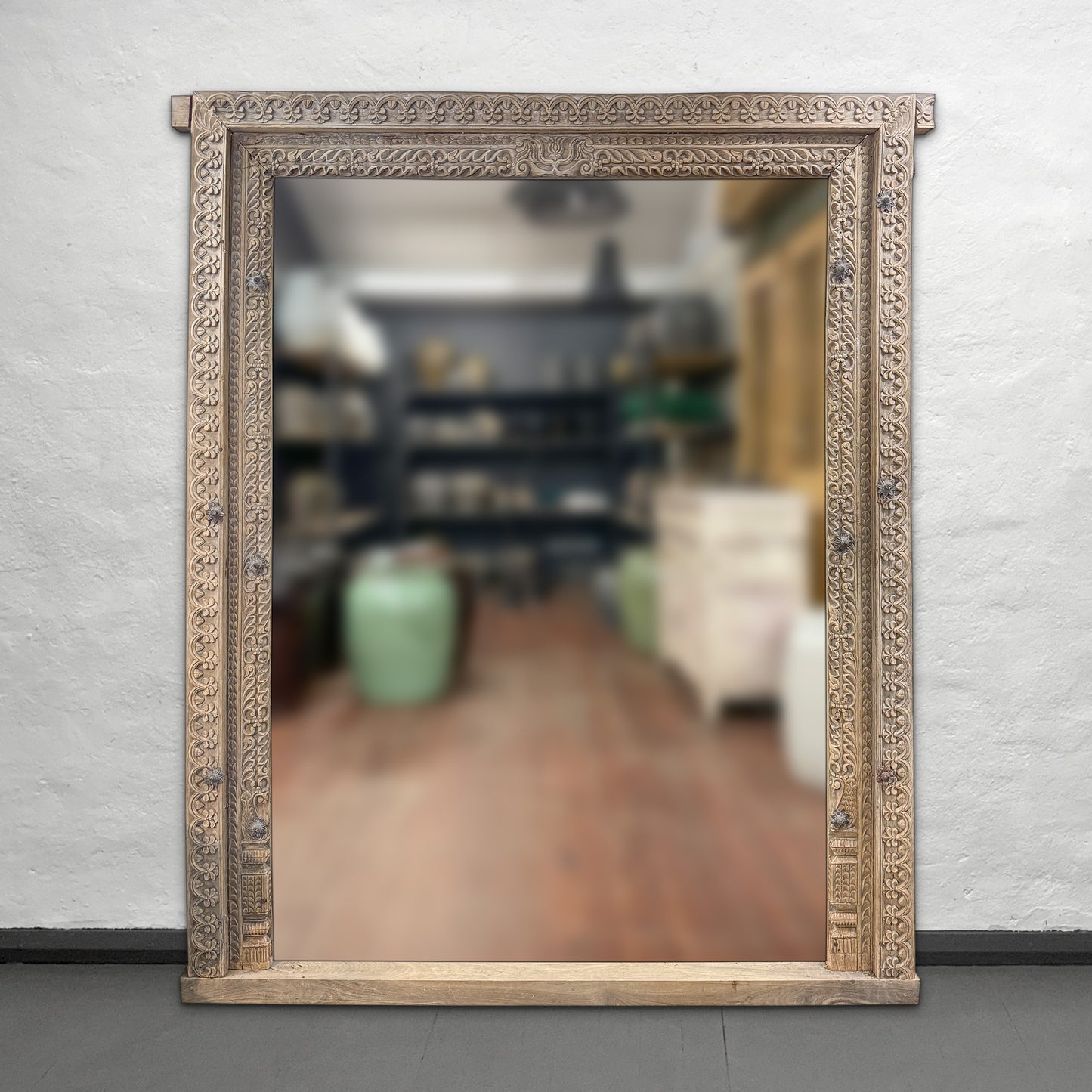 Decorative mirror with an ornate frame on a plain wall.