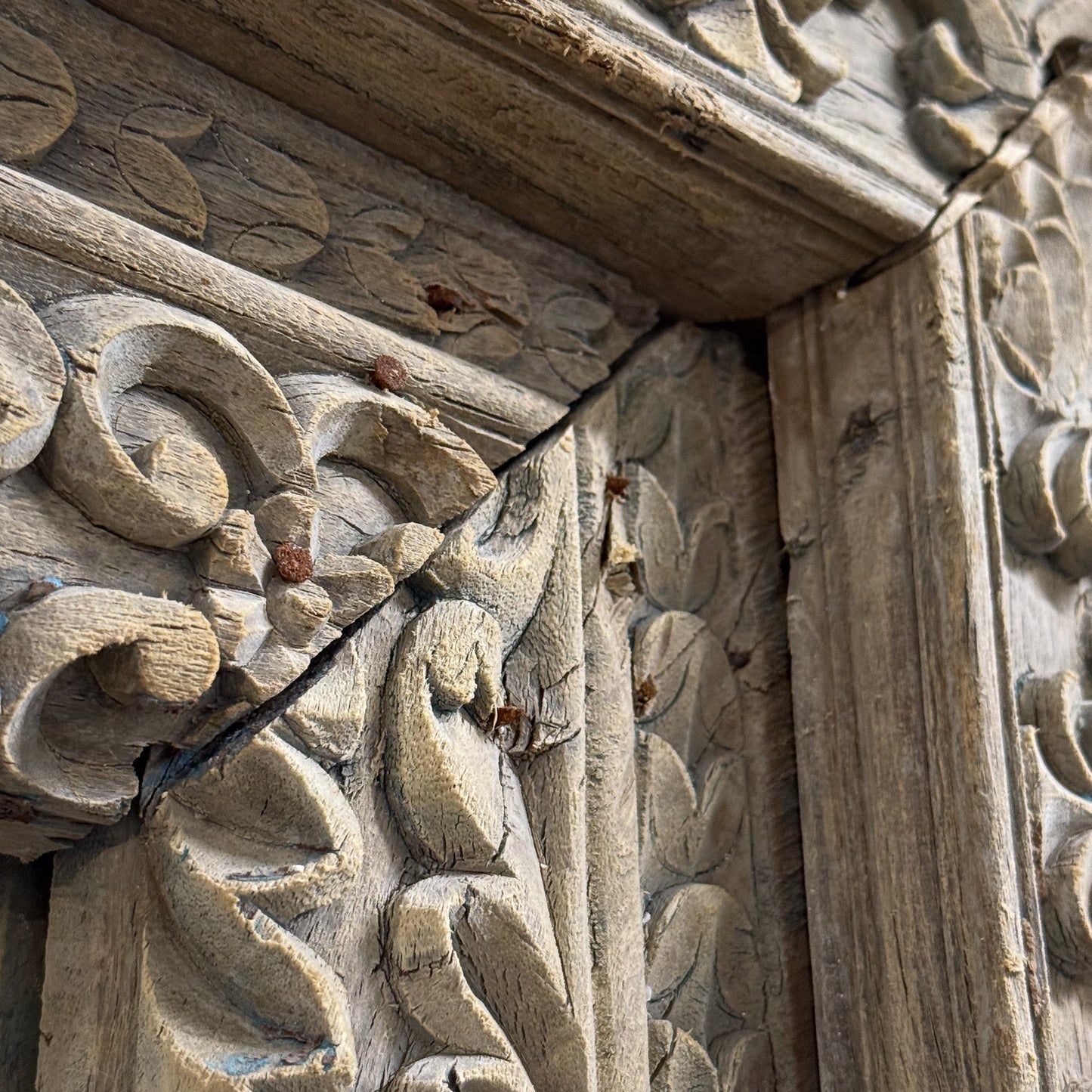Carved wooden panel with intricate patterns and a crack running through it.