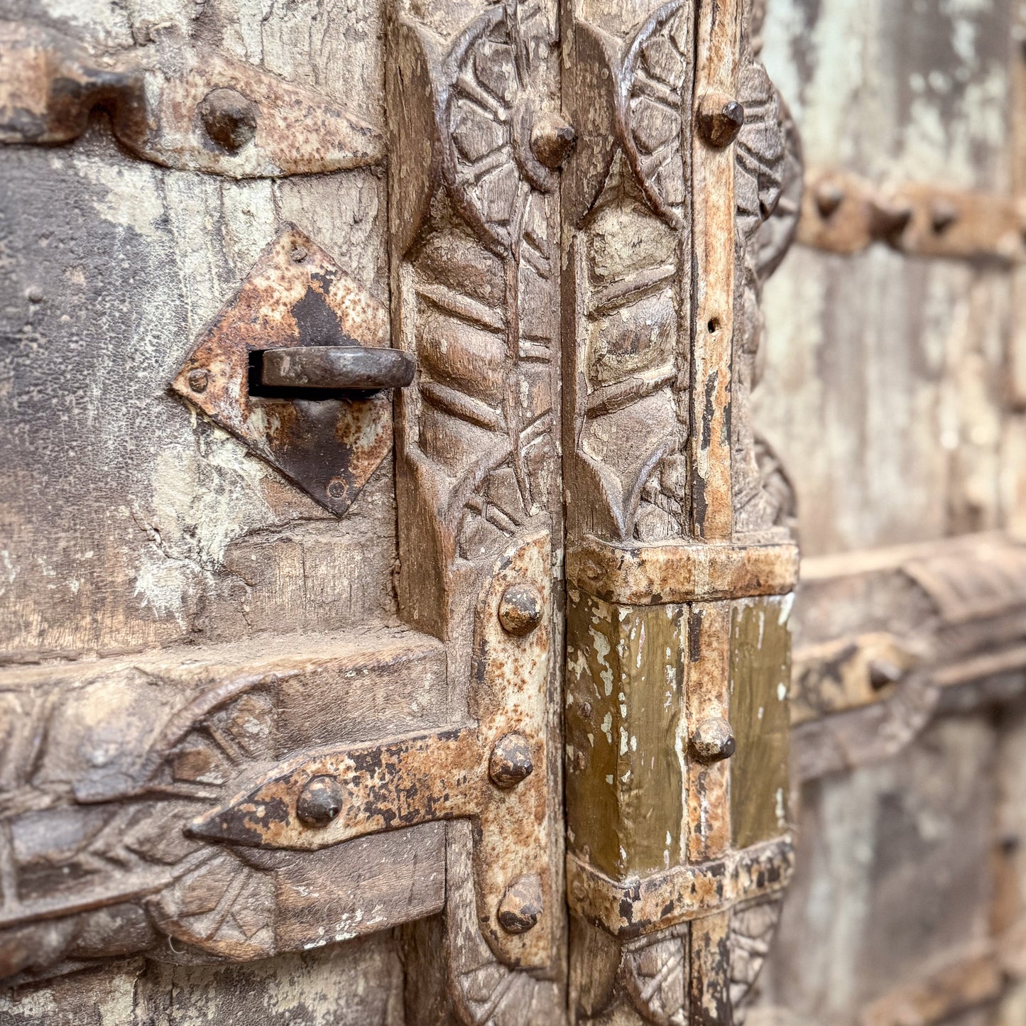Close-up of an old, ornate metal door with intricate designs and rust.