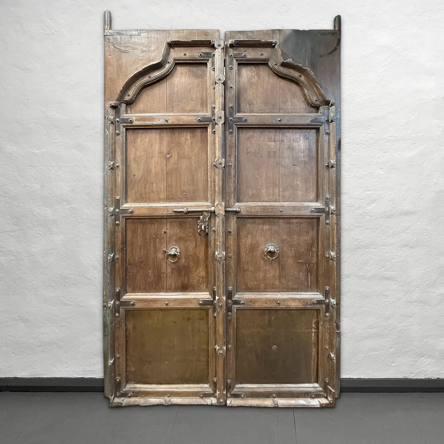 Large wooden door with metal accents on a plain wall