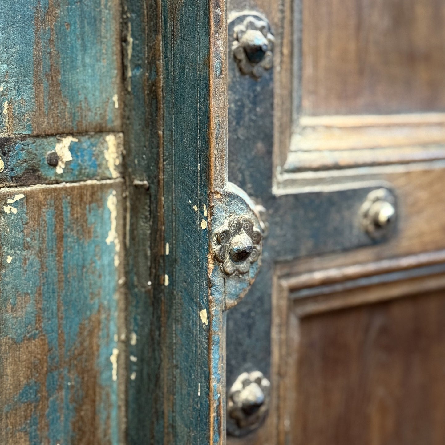 Close-up of an old wooden door with peeling paint and metal hardware.