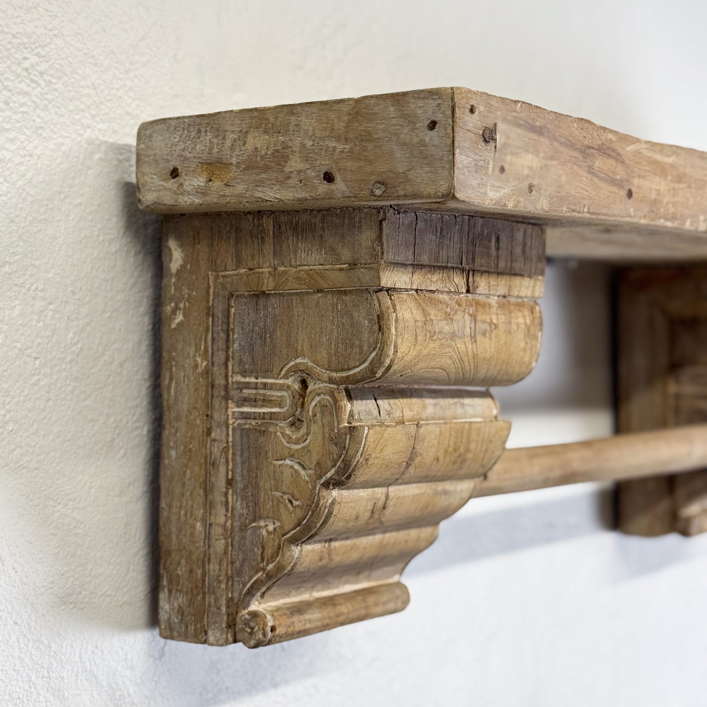 Wooden shelf bracket with intricate design on a white wall