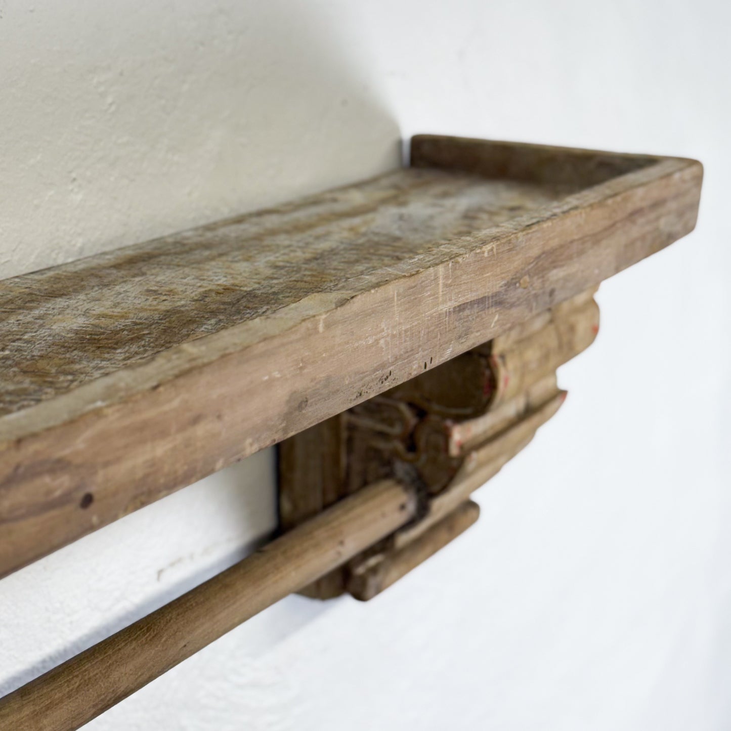 Wooden shelf with rustic design against a white wall