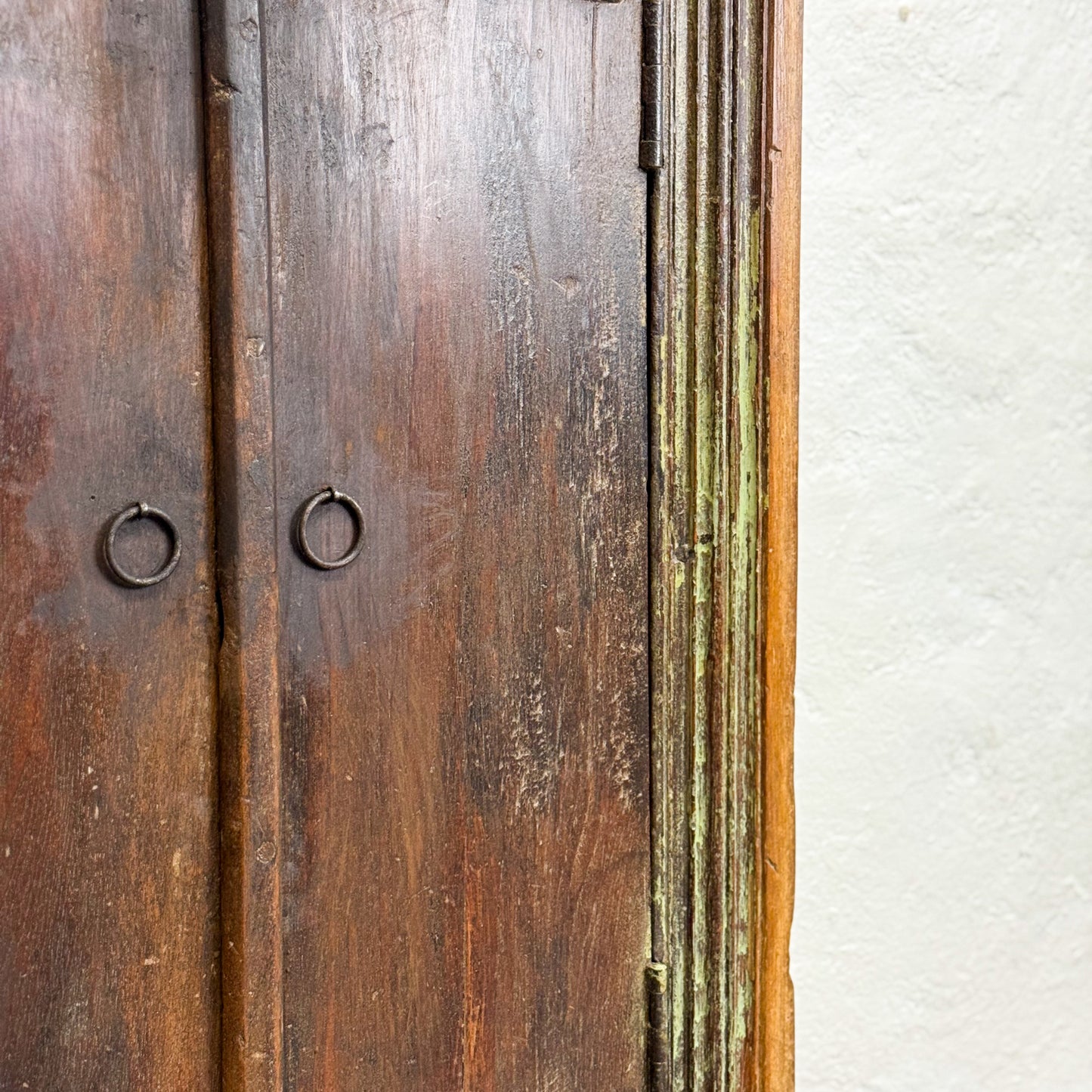 Close-up of a wooden door with metal handles and a white wall background