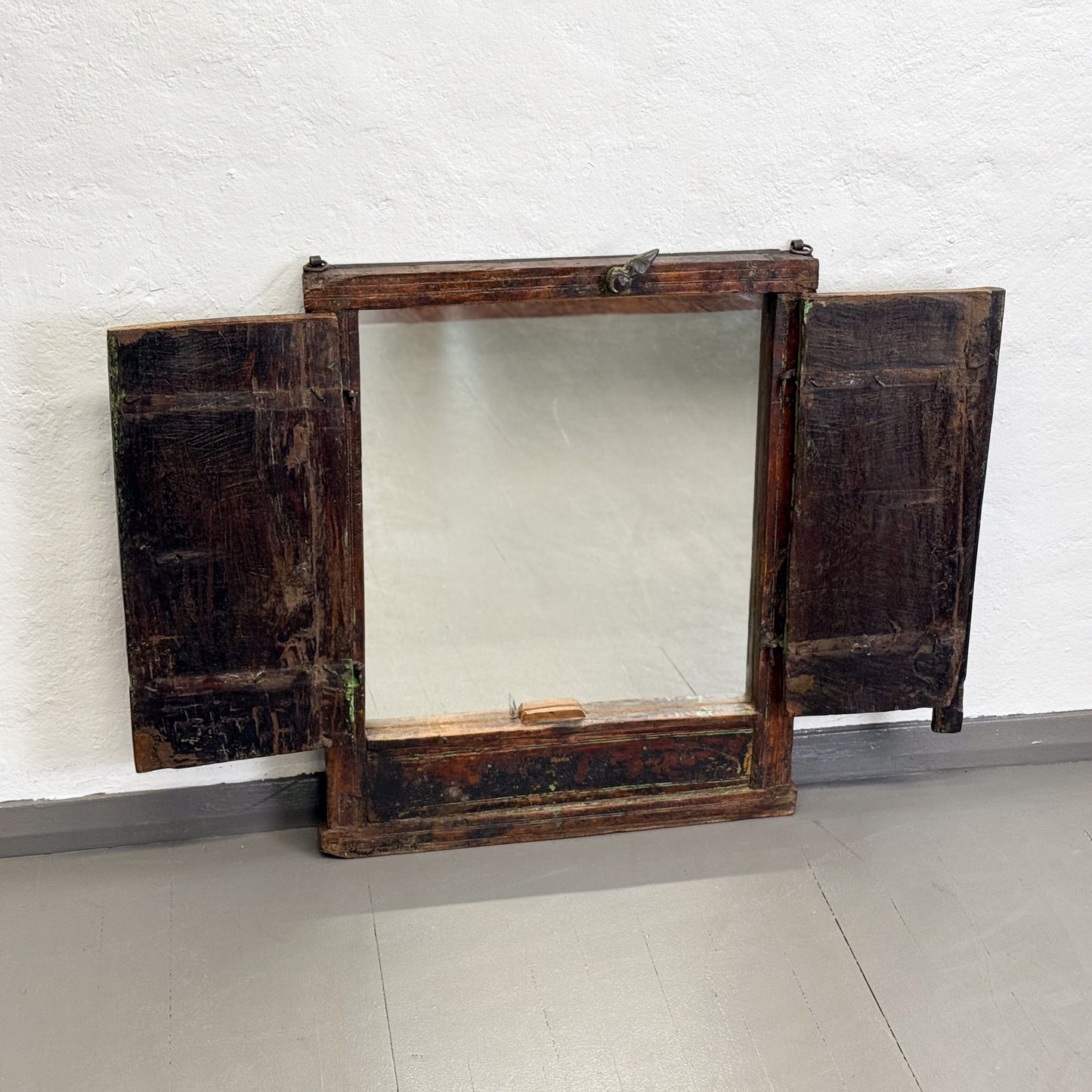 Vintage wooden mirror with hinged doors on a white brick wall background
