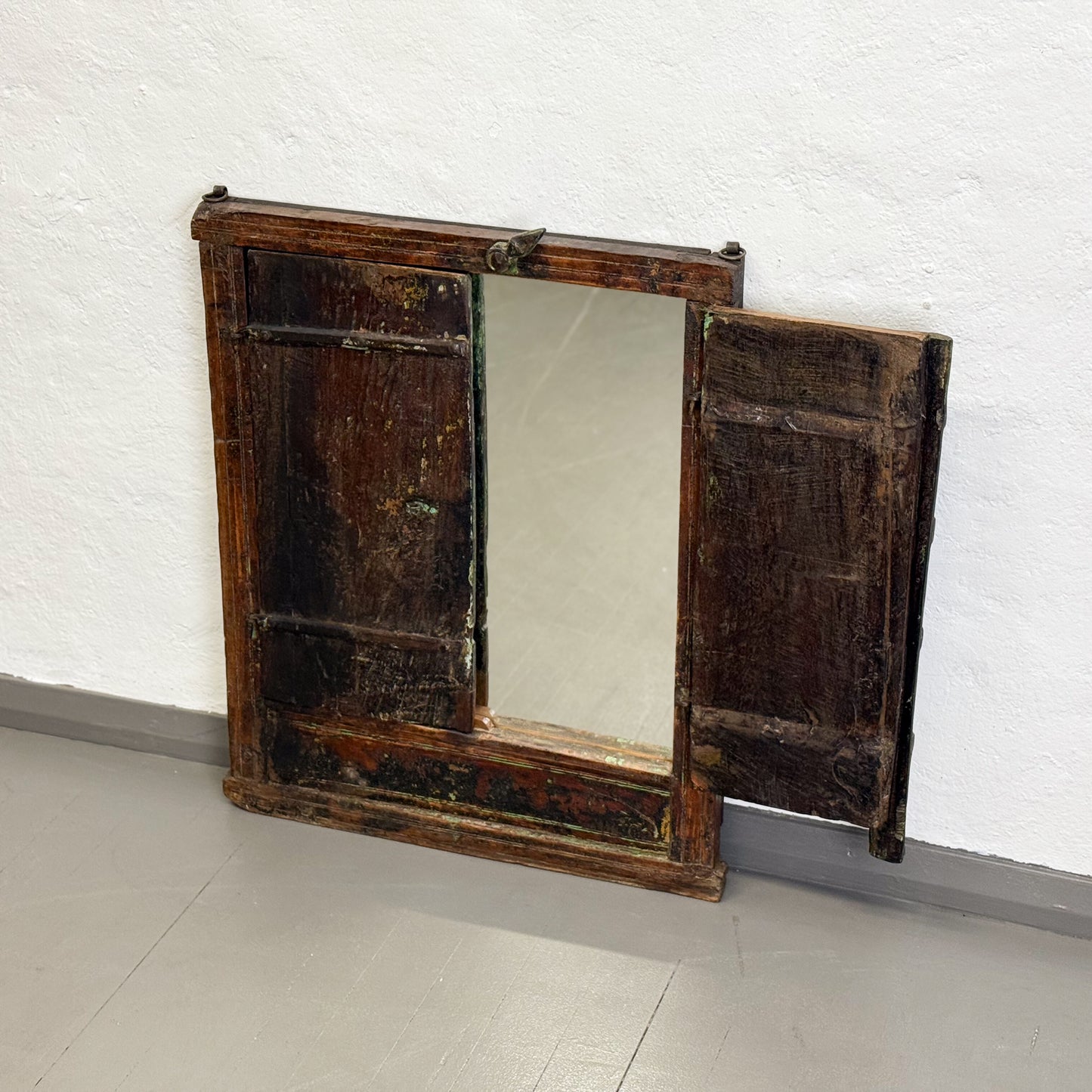 Vintage wooden mirror with a distressed finish on a white wall.