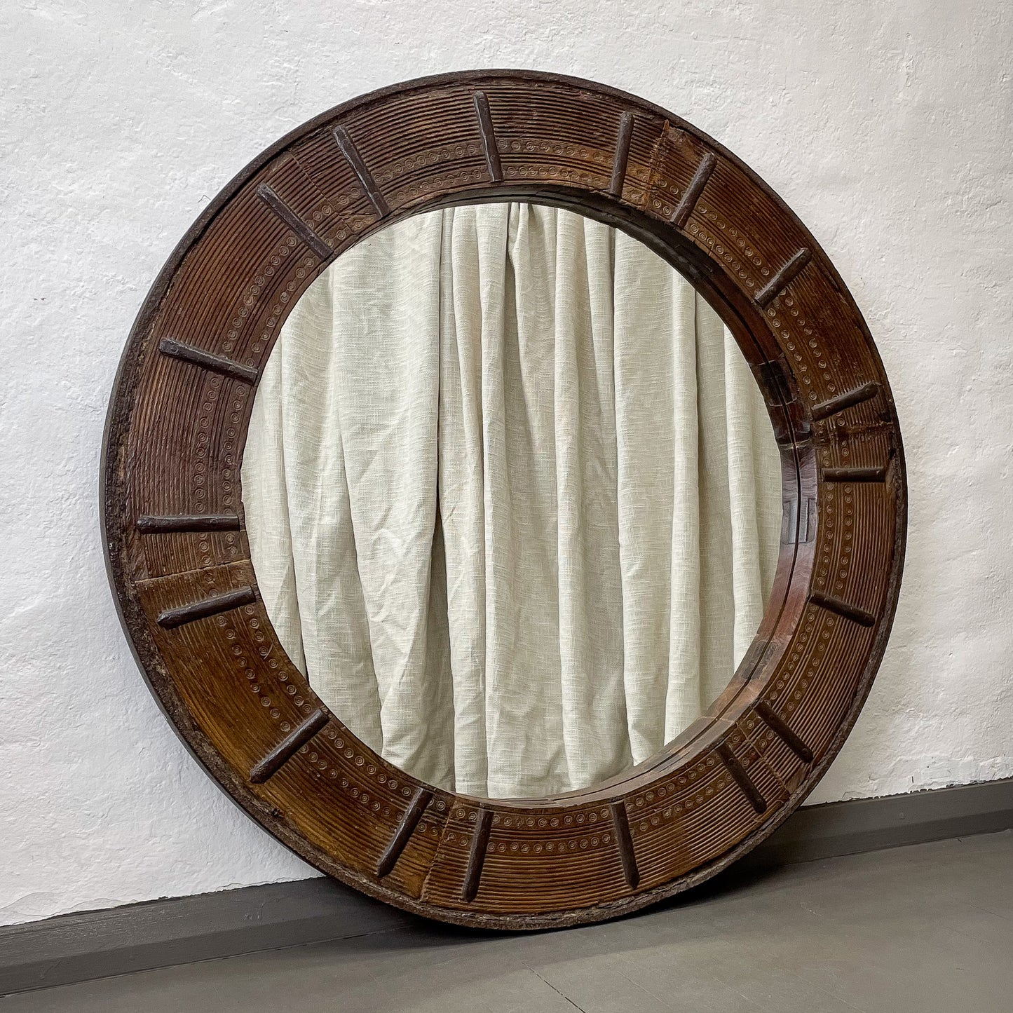 Round wooden-framed mirror on a textured wall