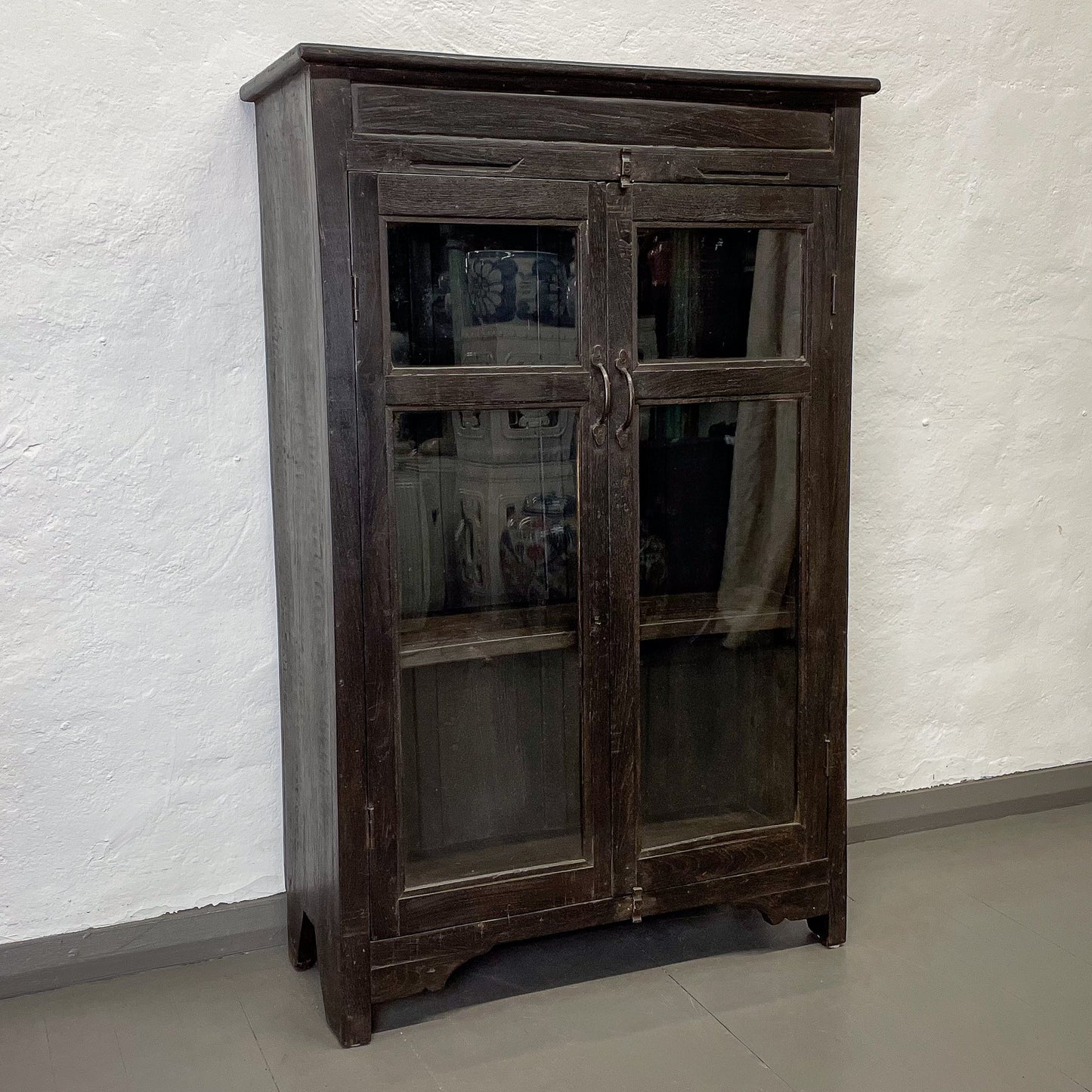 Wooden cabinet with glass doors against a white wall