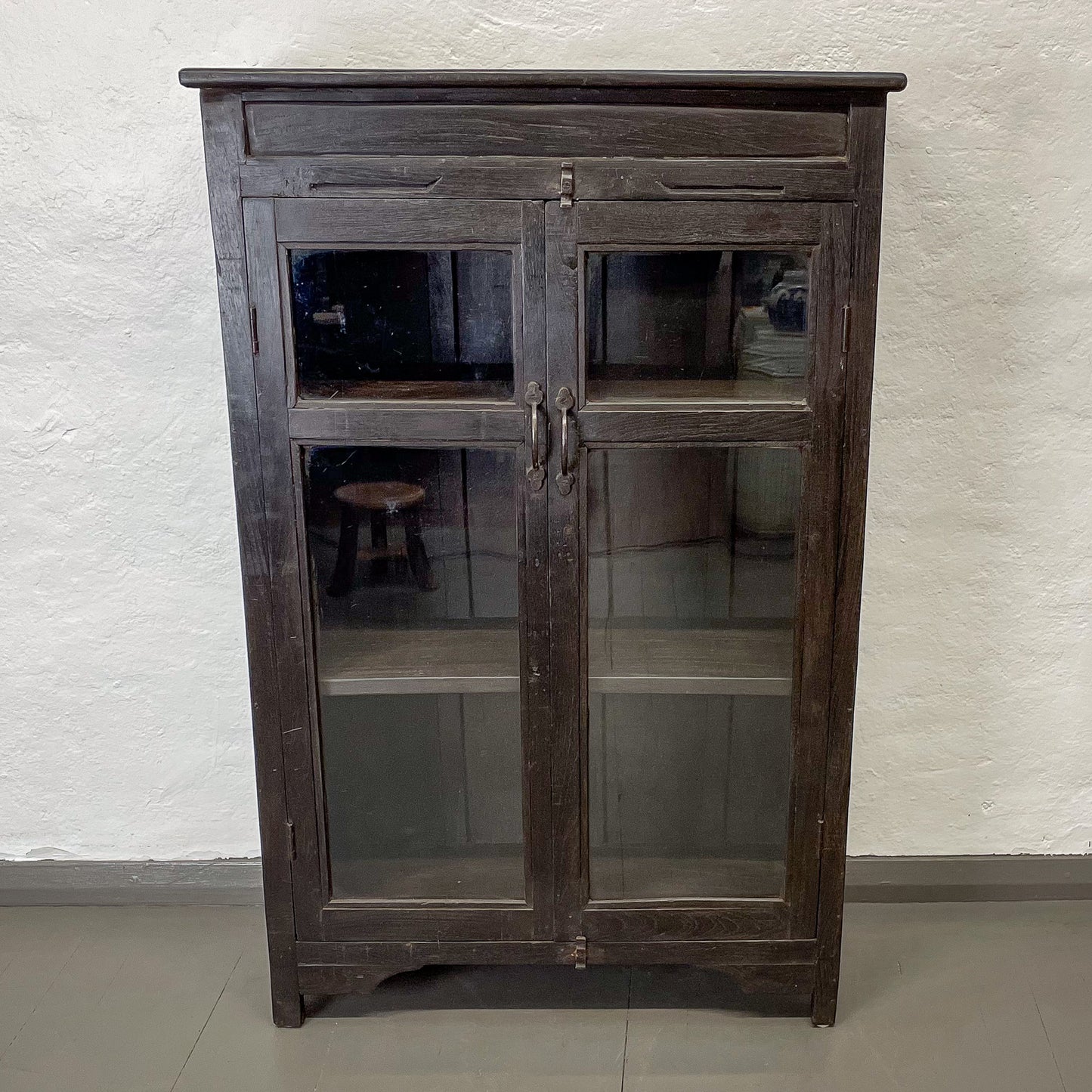 Wooden cabinet with glass doors against a white textured wall