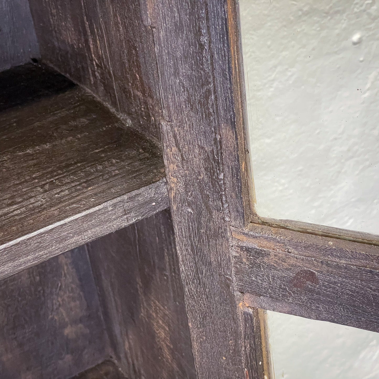 Close-up of a wooden shelf corner with a white wall background