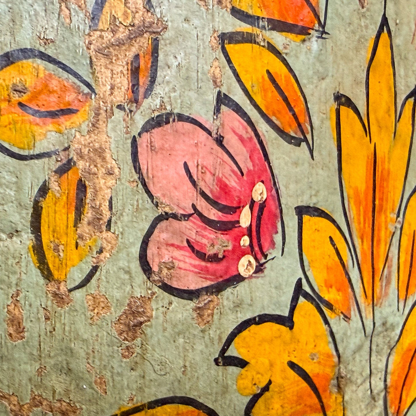 Close-up of a floral design with pink center and orange petals on a textured surface.