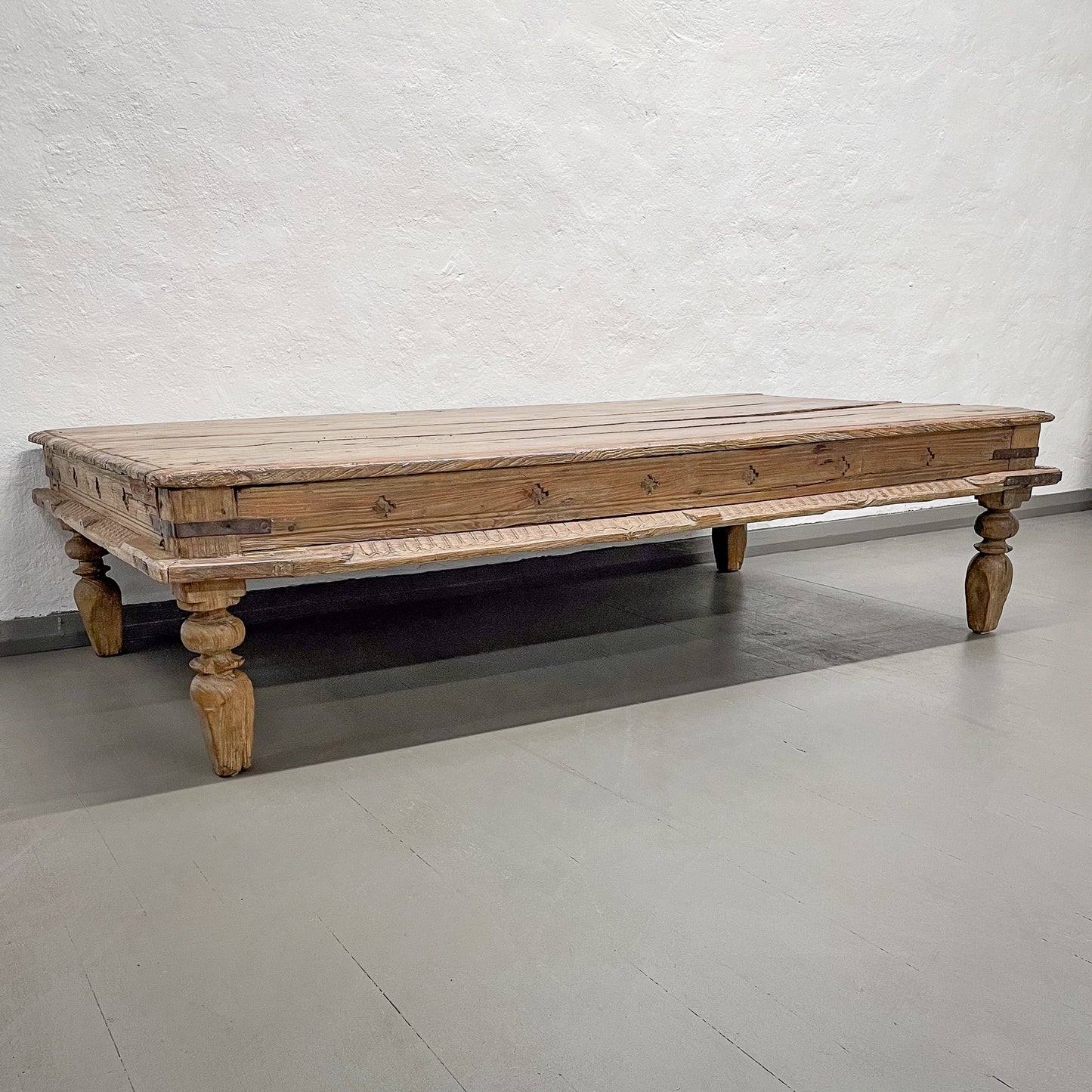 Wooden coffee table with turned legs on a plain floor and wall background