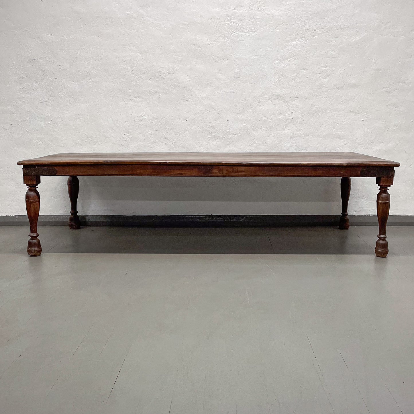 Wooden table with a dark finish on a plain floor and white wall background