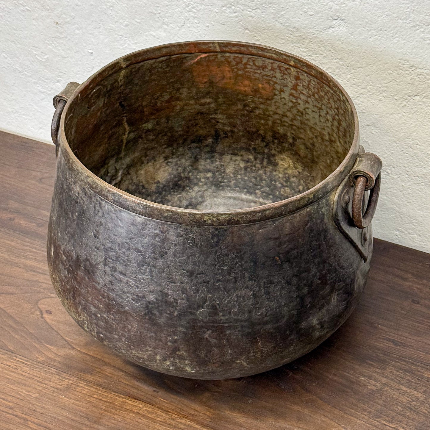 Vintage metal pot on a wooden surface with a white wall background