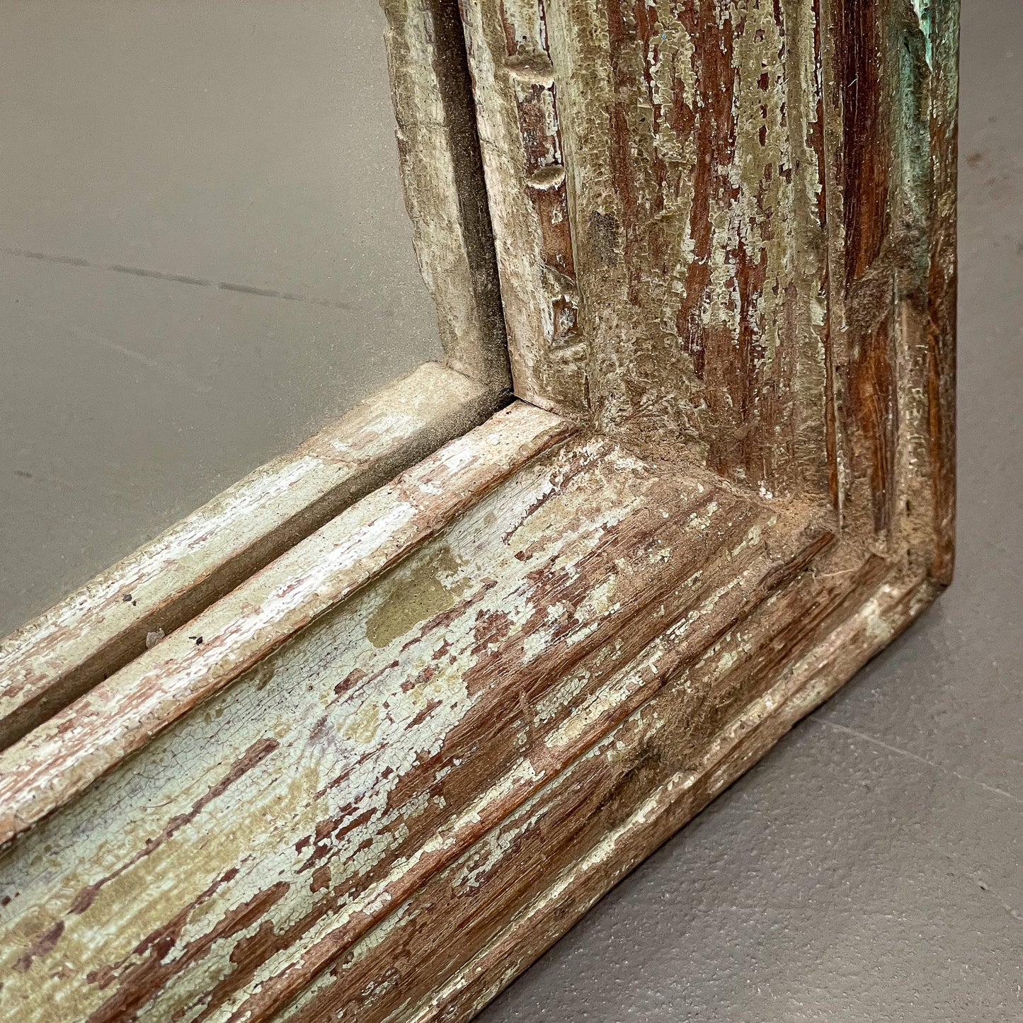 Close-up of a weathered wooden frame with peeling paint on a neutral background
