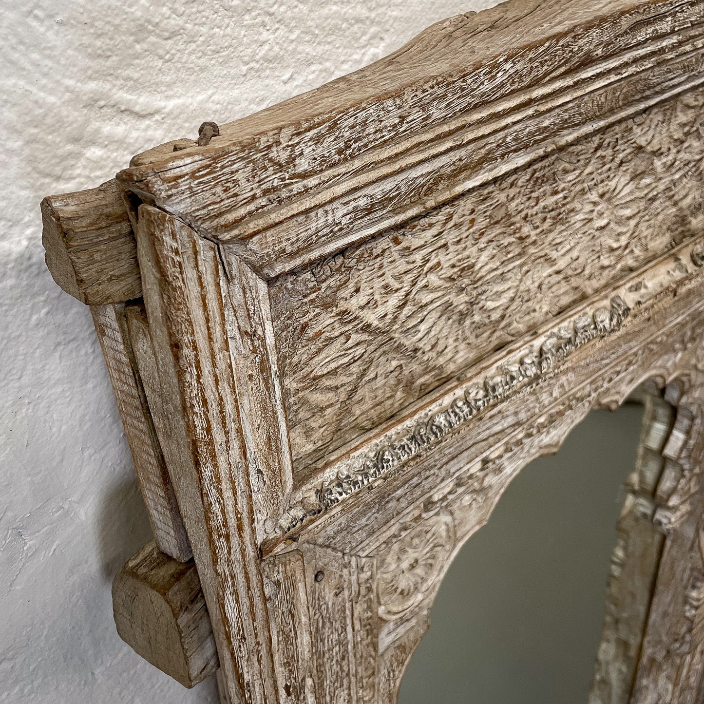 Close-up of an ornate wooden mirror frame with a textured surface.