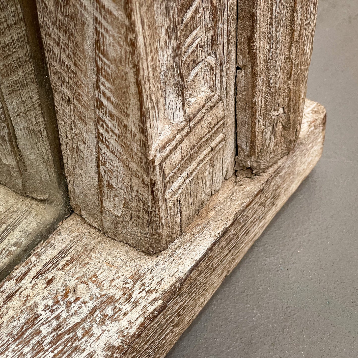 Close-up of a wooden architectural detail with intricate carvings on a gray background