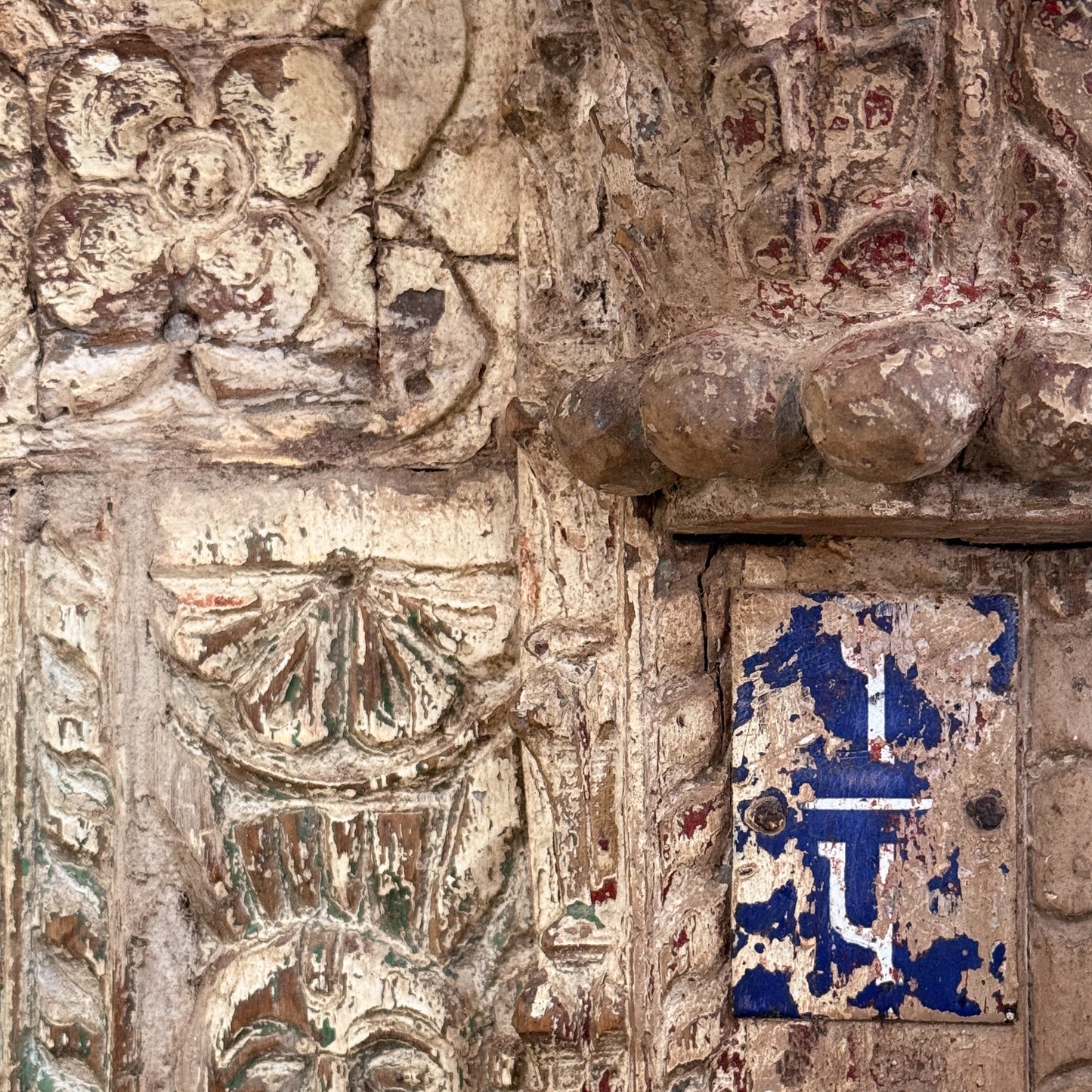 Decorative stone wall with intricate carvings and a blue and white tile.