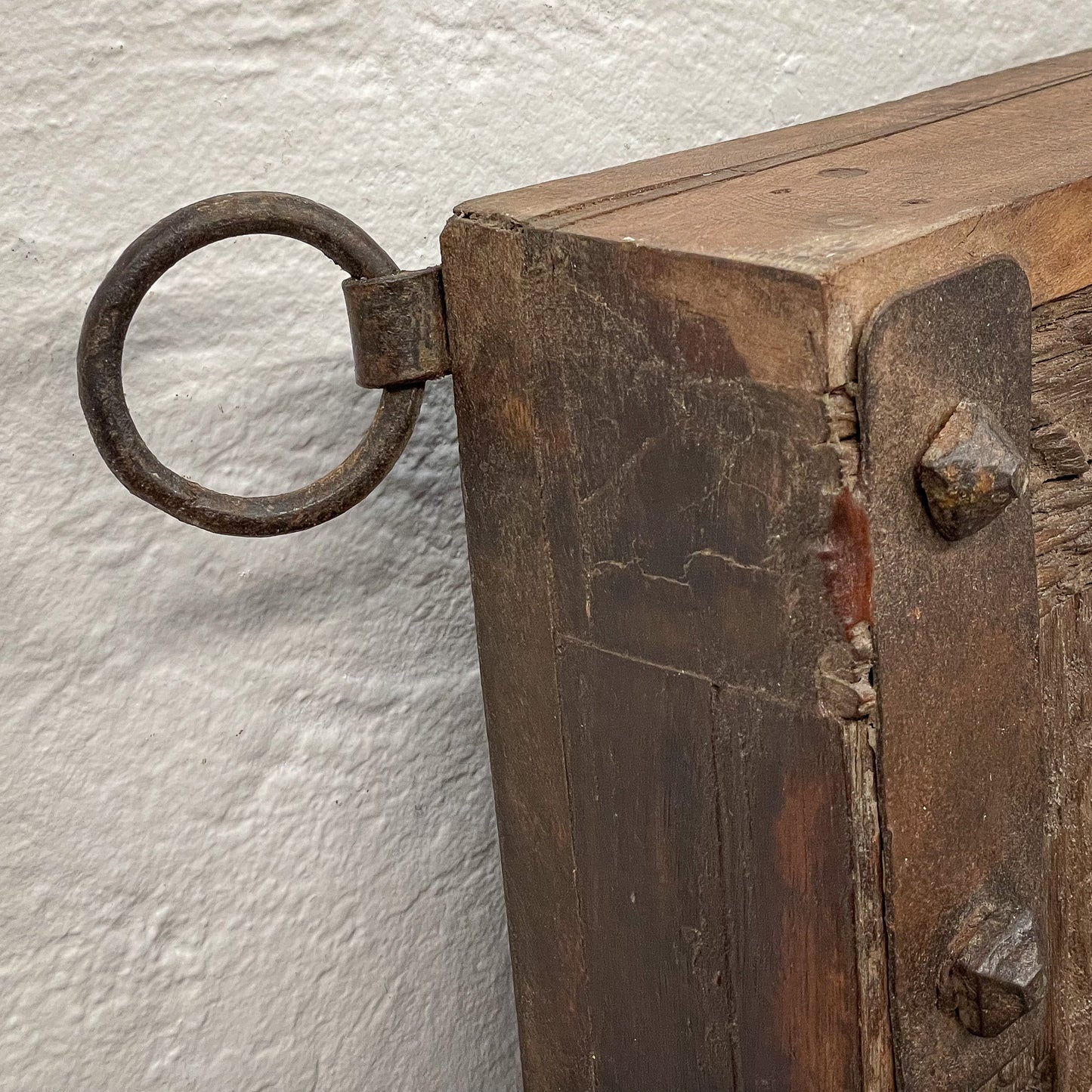 Close-up of a wooden box with a metal handle on a textured white background