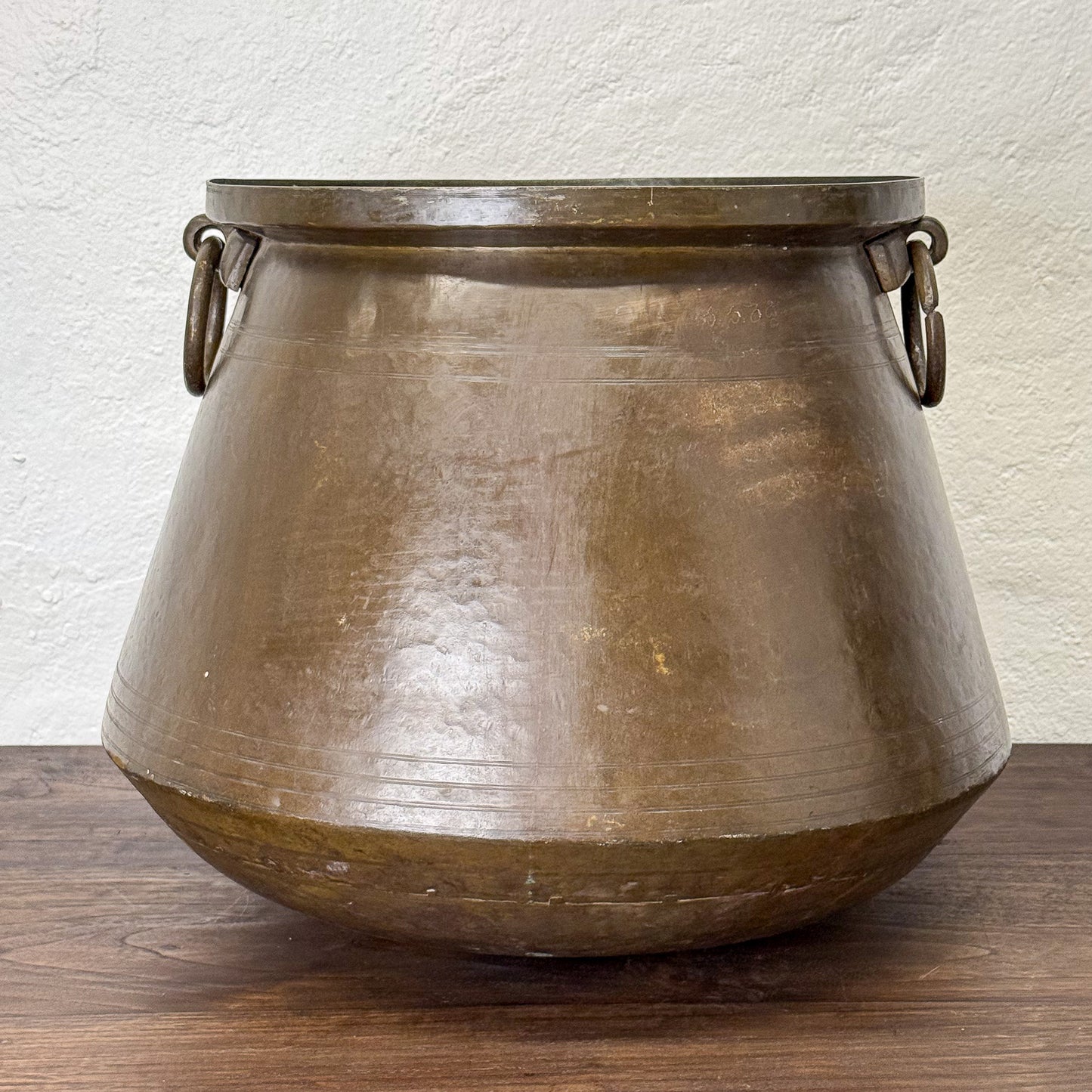 Bronze pot with handles on a wooden surface and light background