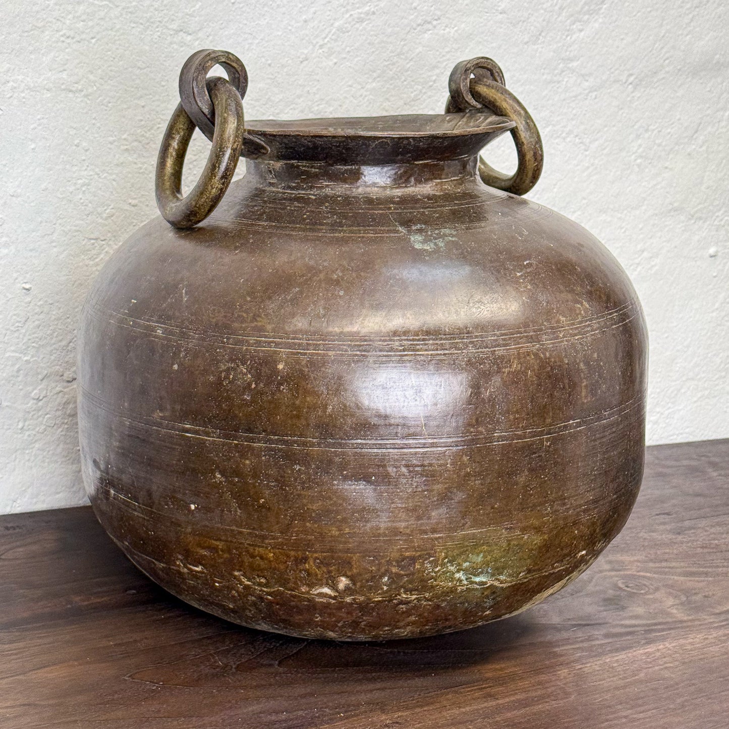 Bronze vase with ring handles on a wooden surface