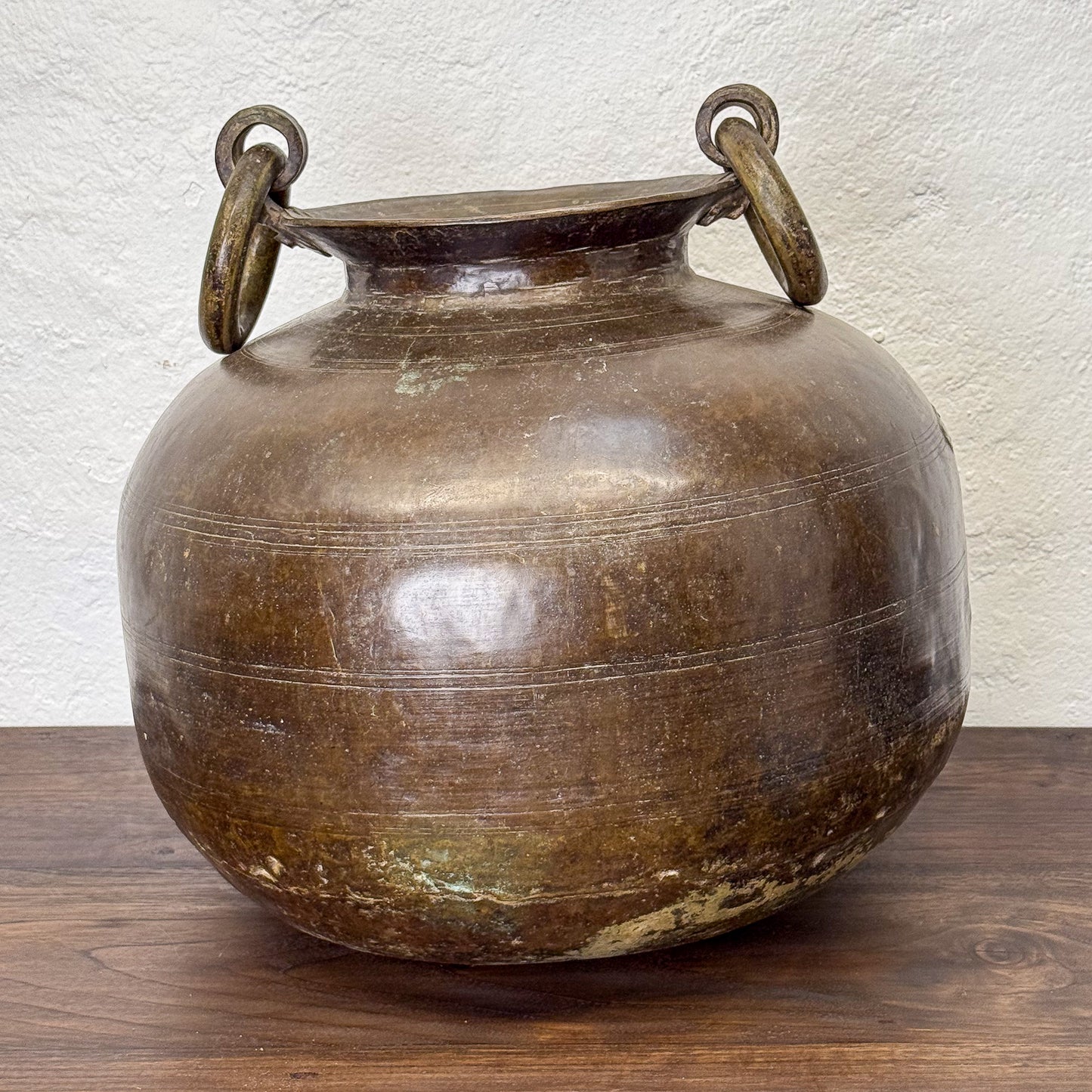 Bronze pot with handles on a wooden surface and light background
