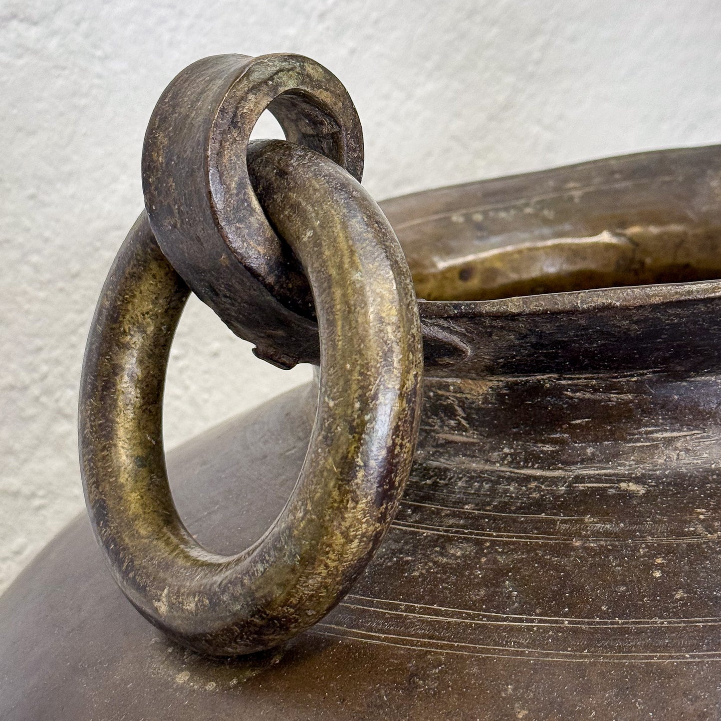 Bronze pot with ring handles on a wooden surface