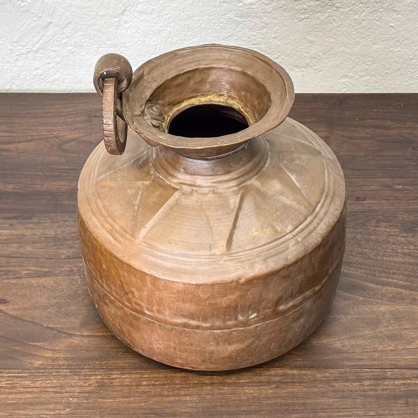 Bronze pot with handle on a wooden surface